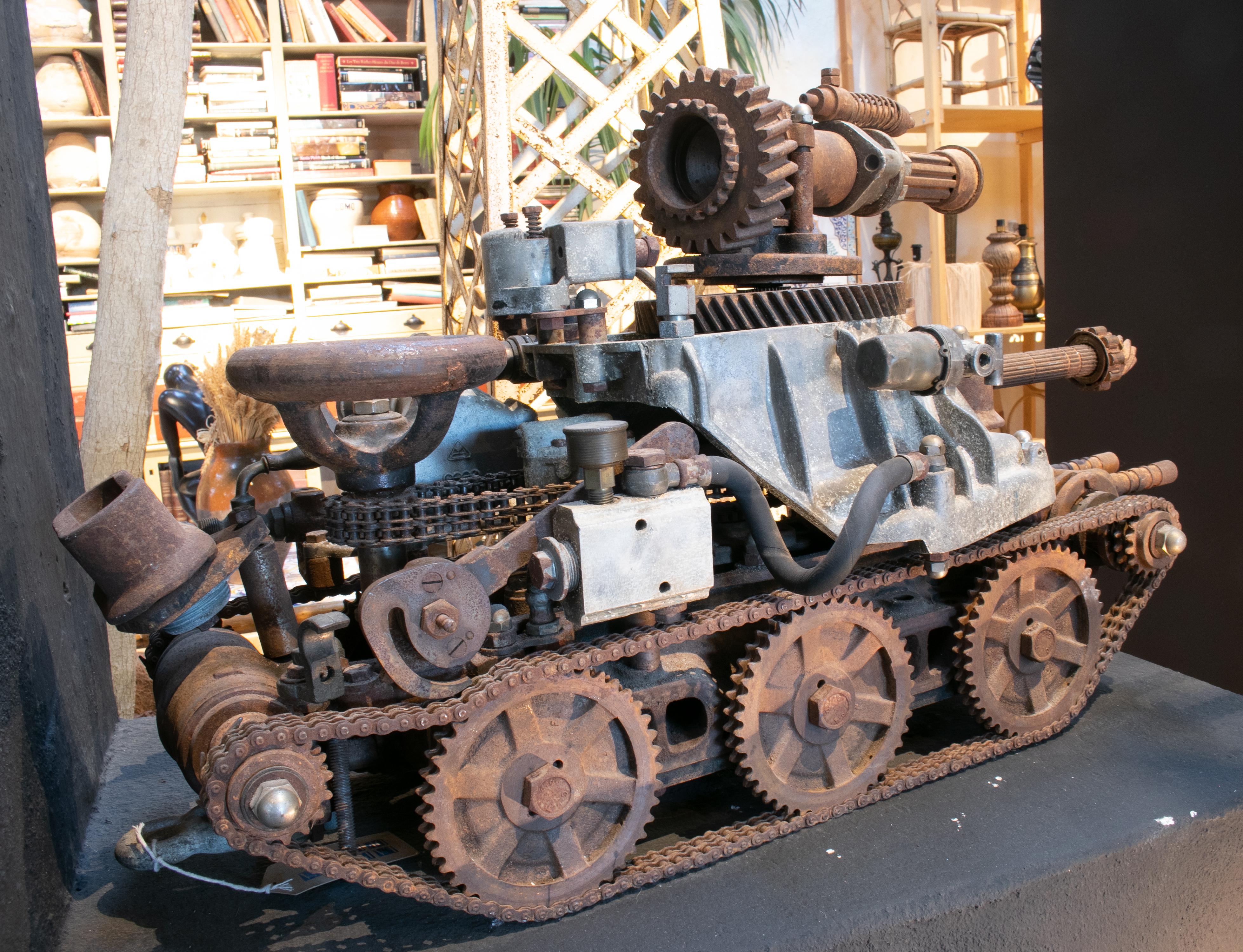Skulptur eines Panzers mit Kanone aus den 1970er Jahren, hergestellt aus verschiedenen alten mechanischen Metallteilen: Autos, Fahrräder, Rasenmäher etc.
 