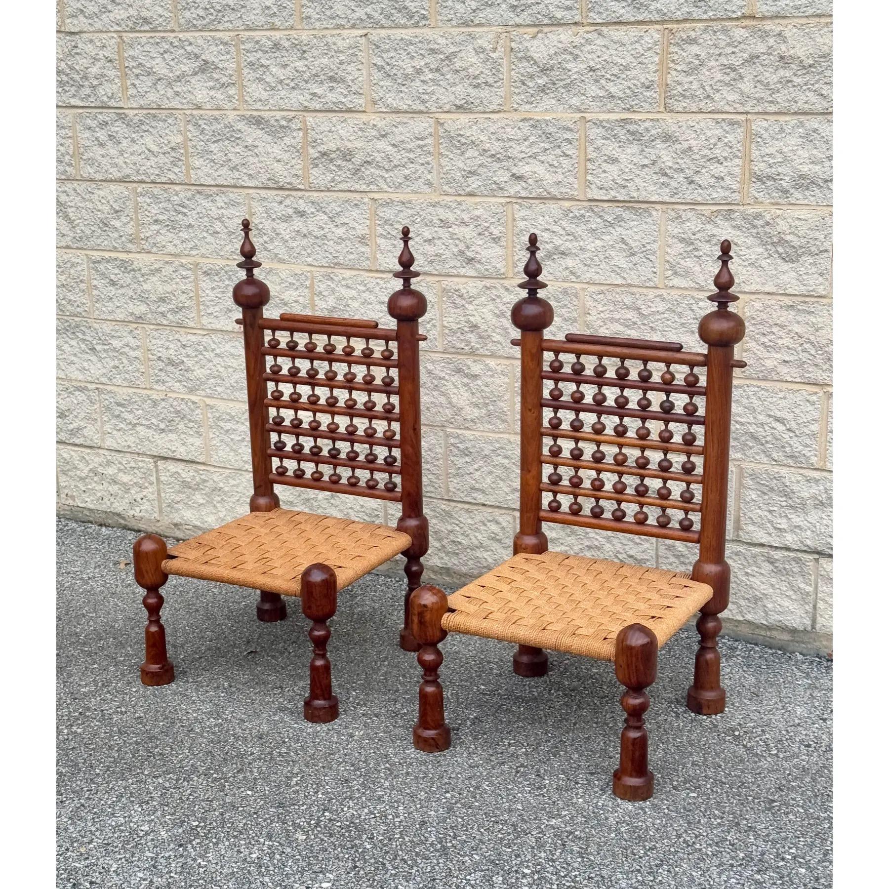 Pair of 1970s teak Punjabi chairs featuring intricate hand-carved detailing and seats woven with durable rope. 

