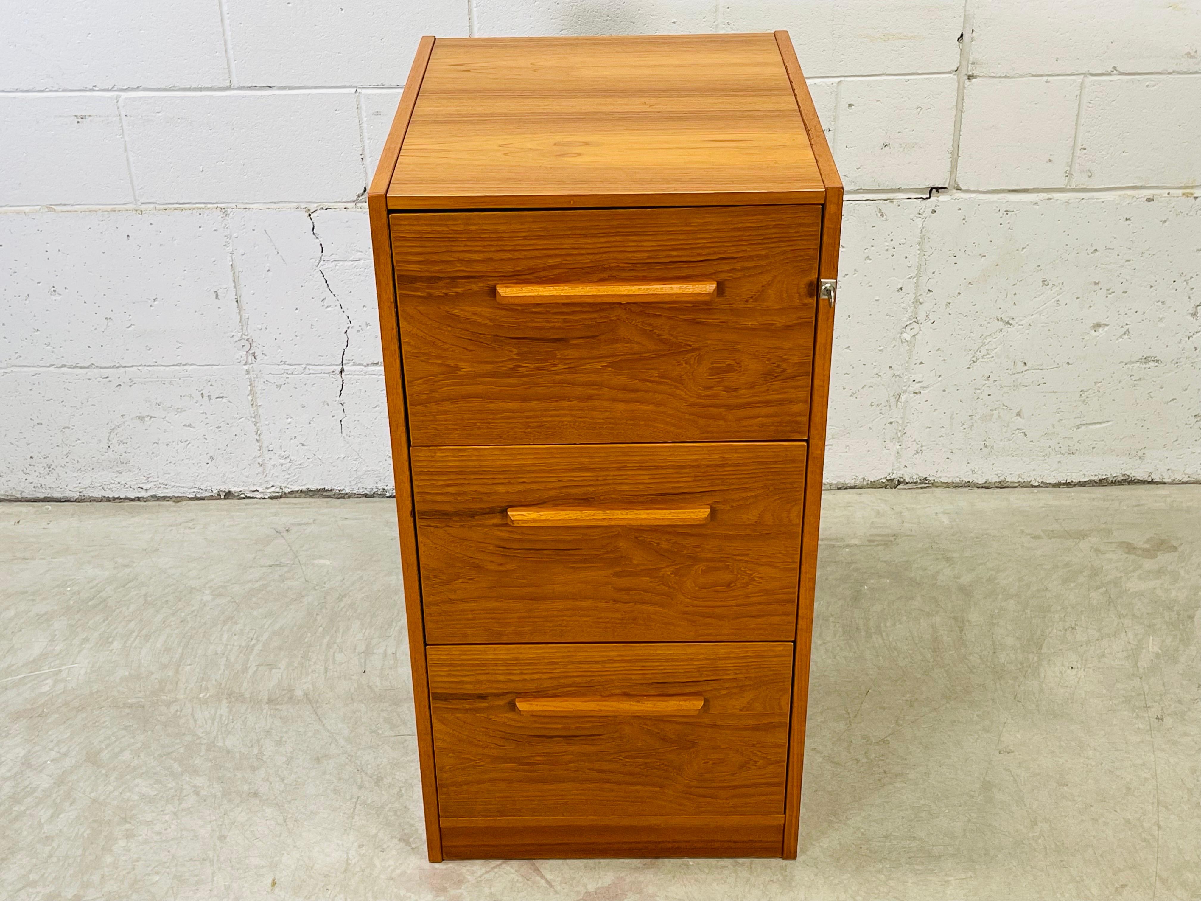 Vintage 1970s teak wood three drawer filing cabinet. All three drawers hold 15”W file folders (legal size) and comes with one key for the lock. The lock is operational. The back of the cabinet is finished. All drawers open and close freely. No marks.