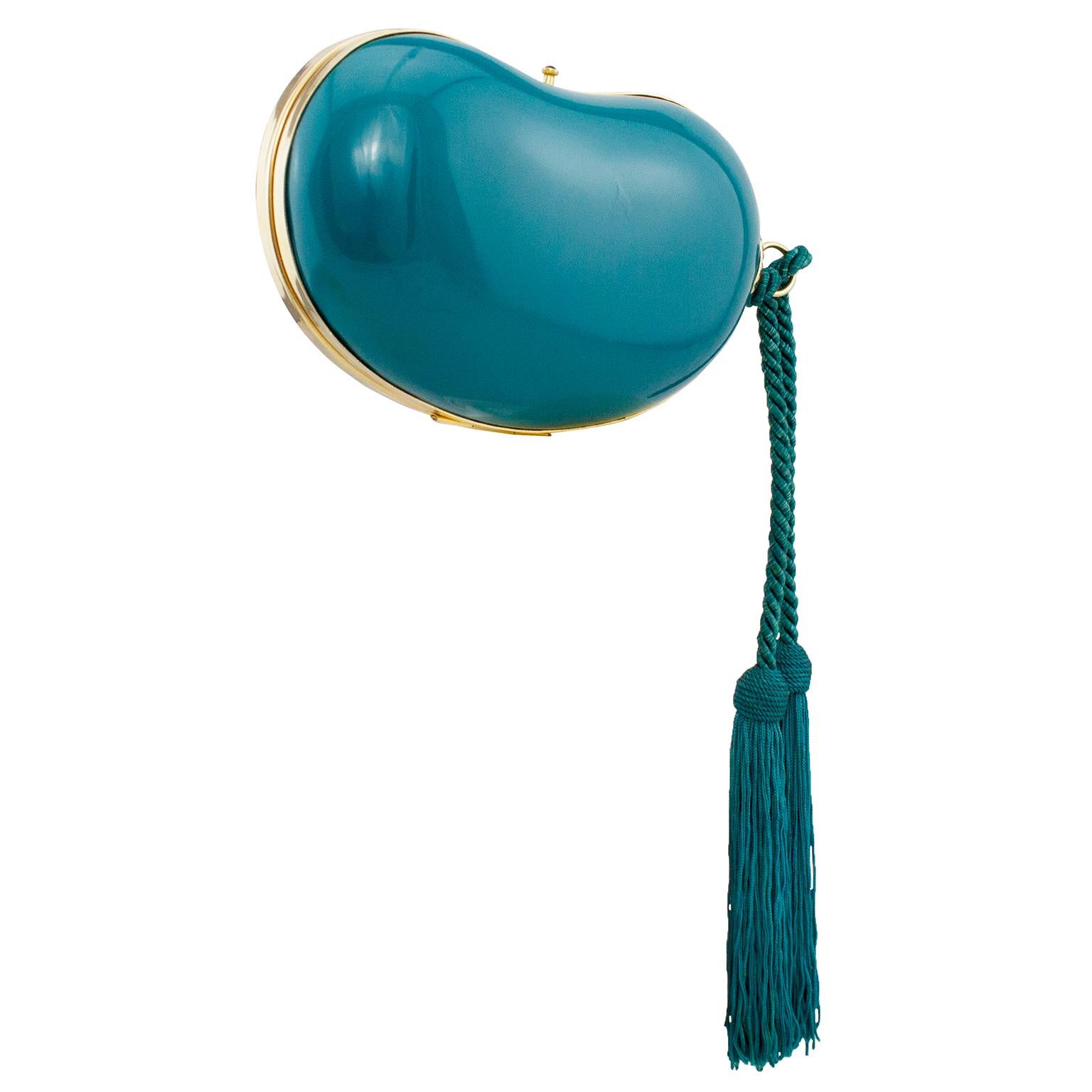 Fabulous hard clutch dating from the 1970s. Shaped like the Elsa Peretti bean, this is in a rich deep teal colour and is contrasted with gold tone metal trim and hardware. Twisted  teal silk rope with two large tassels. Tiny black cabochon clasp