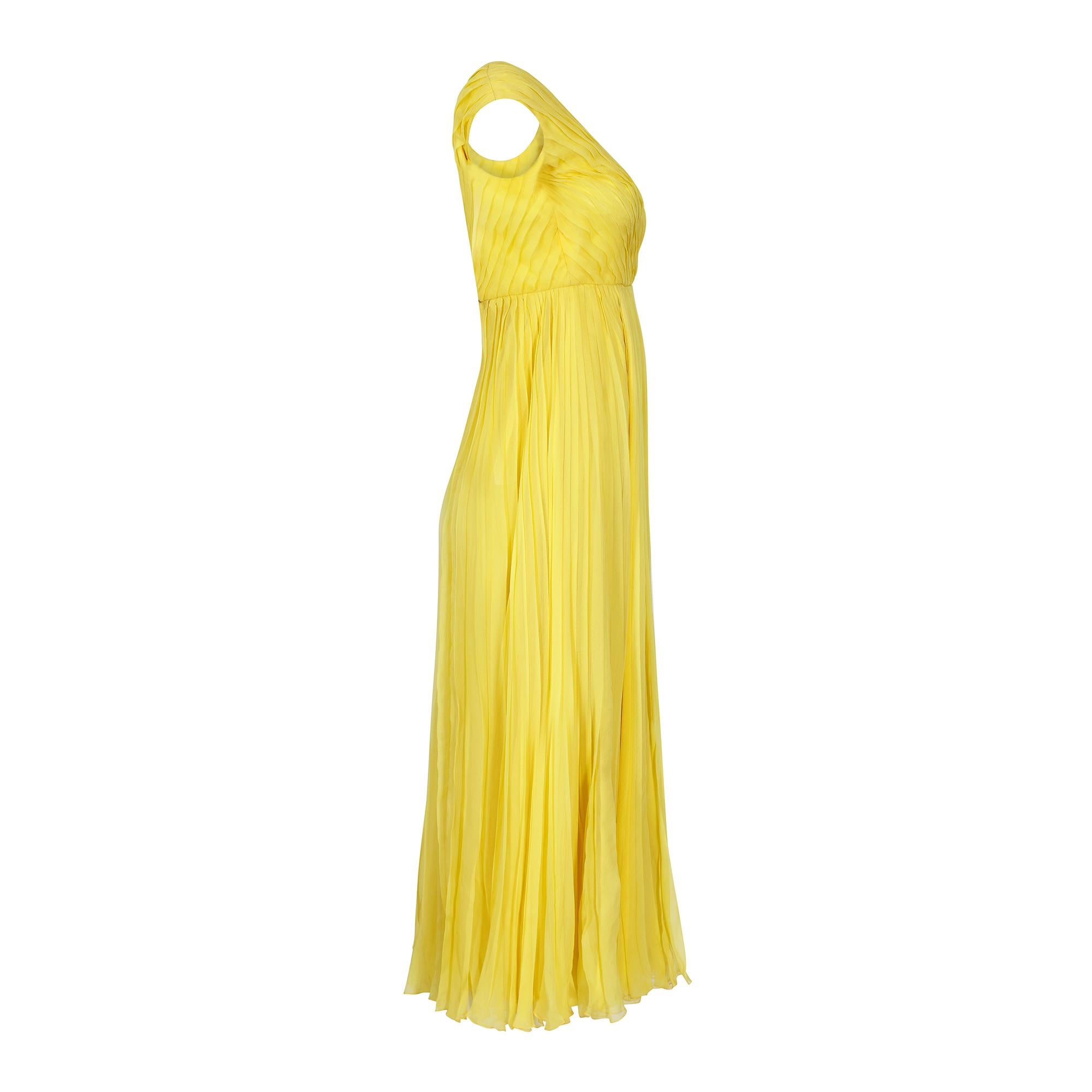 Few can claim to share the standards of renowned French couturier Ted Lapidus. This dress is made of a yellow silk crepe with the most superbly executed knife pleats and an elegant sleeveless deep V neck design with a high empire waist. This