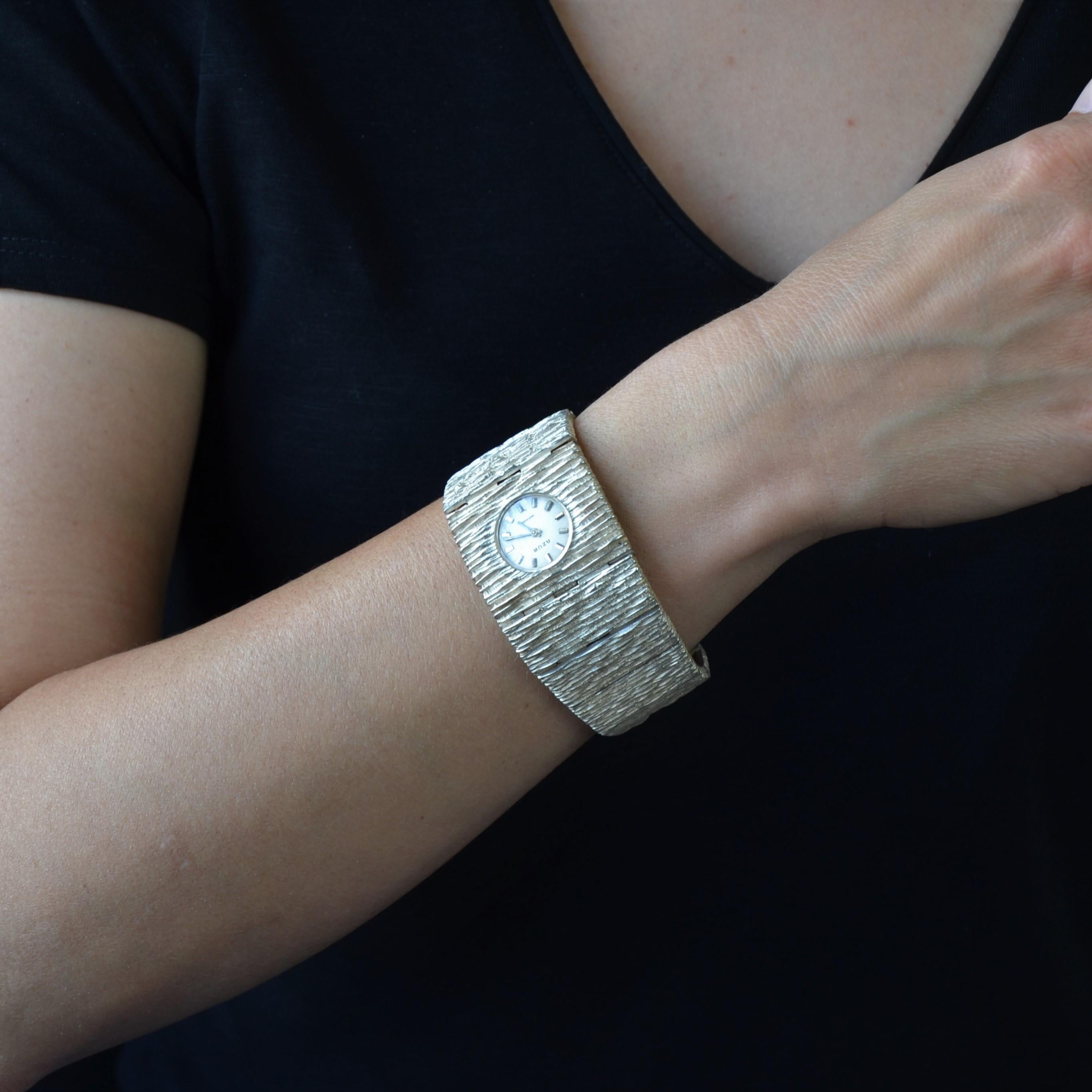 Watch in silver, swan hallmark.
Important and imposing retro watch in silver, it is formed of a wide bracelet in fall, with textured and amatized silver. The clasp is a scale.
The watch is round in shape, the light gray brushed back, marked 