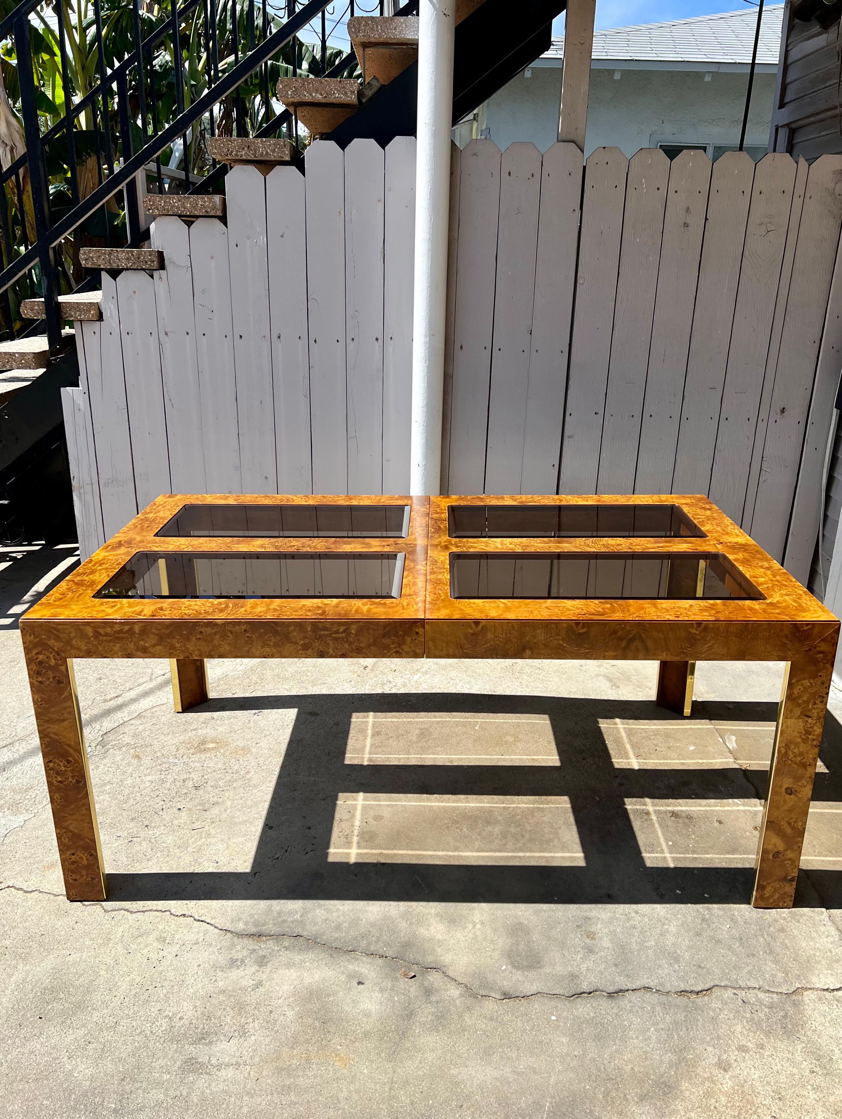 An elegant dining table that will never go out of style. Rich burl throughout with gold detailing and beveled smoked glass inserts. Easily expands to 110” with both 20” leaves (included) inserted. The piece is stamped Thomasville and October 1978.