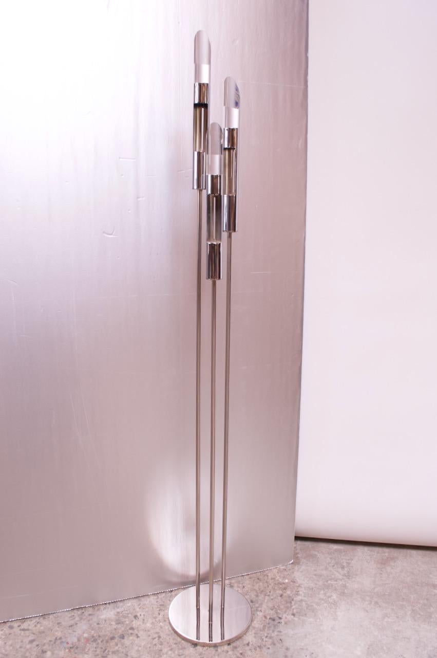 Unusual circa 1970s, USA floor lamp featuring three chrome rods supporting cylindrical chrome fixtures with lucite prism inserts. Each prism has a blue disc affixed to the base, which reflects a blue light at certain angles. The fixtures have 360