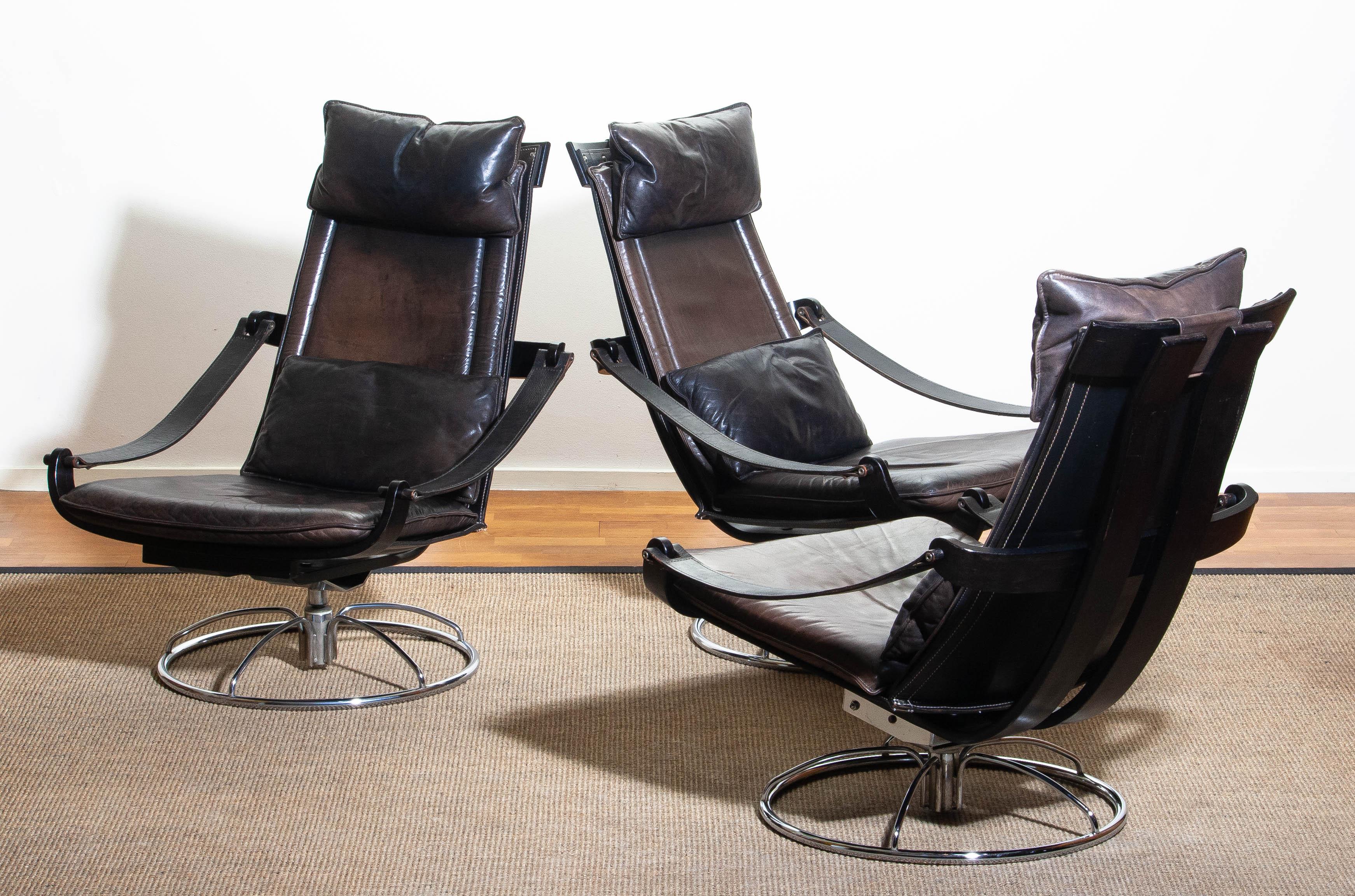 Extremely beautiful and artistic set of three swivel easy / lounge chairs designed by Åke Fribytter for Nelo Sweden.
These high quality chairs features a plywood frame and Brown leather cushions and a chromed metal base.
One chair has got an
