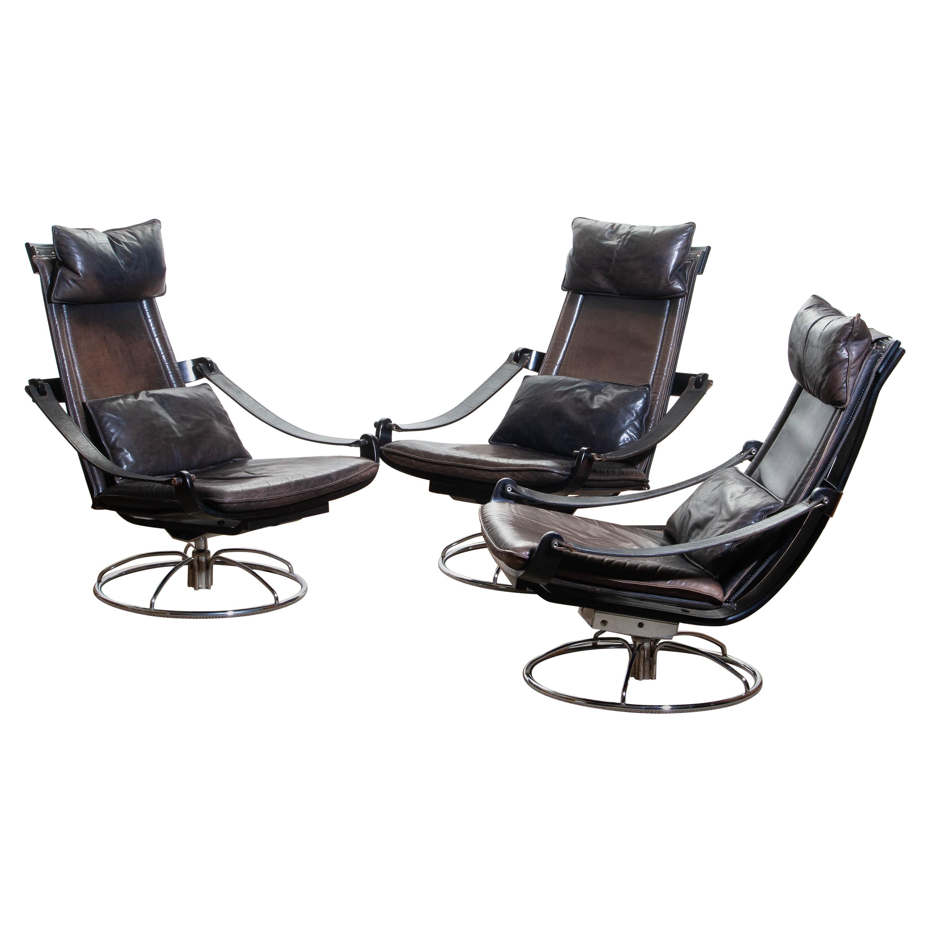 Extremely beautiful and artistic set of three swivel easy / lounge chairs designed by Åke Fribytter for Nelo Sweden.
These high quality chairs features a plywood frame and Brown leather cushions and a chromed metal base.
One chair has got an