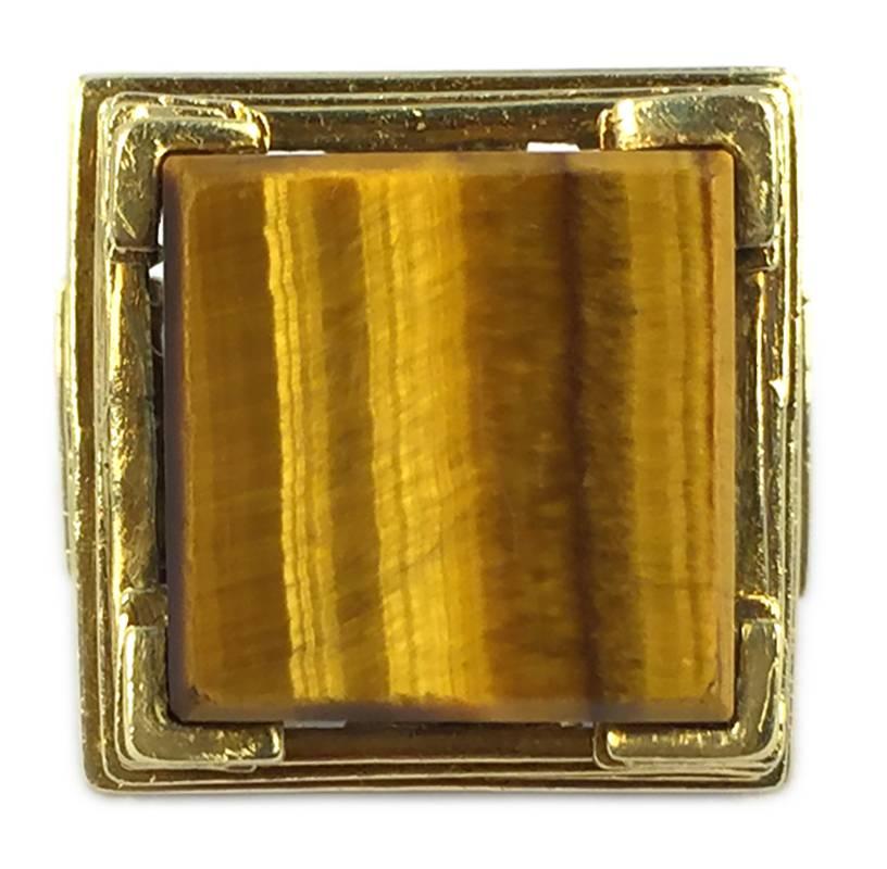 An unusual cocktail ring, showcasing a cubic tiger eye element, supported by a pyramidal step structure in 18kt yellow gold. Circa 1970.