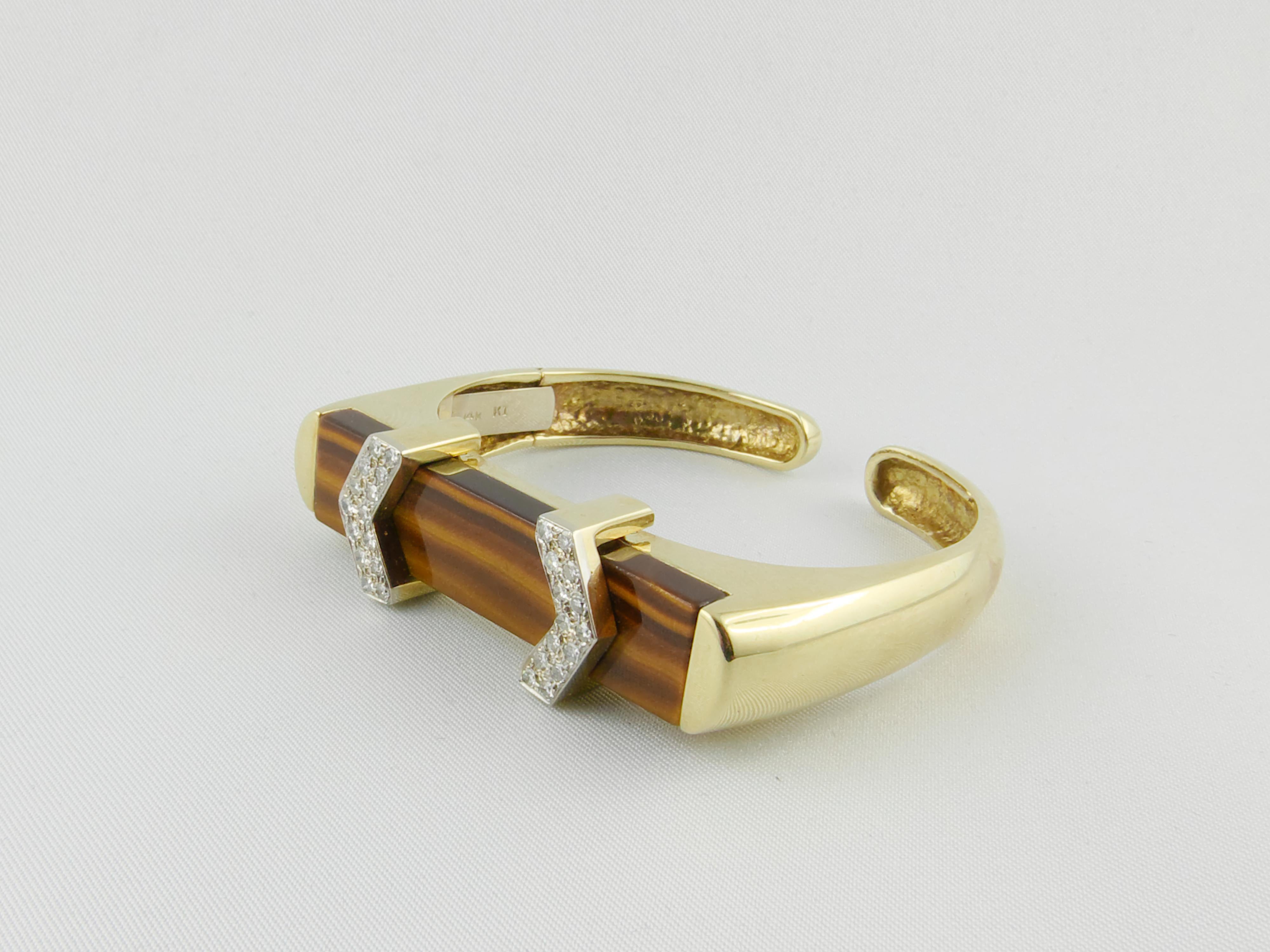 This stylish and glamourous 1970s Bangle Bracelet is finely crafted in Yellow Gold with a Tiger’s Eye  central insert and it is set with two arrow-shaped lateral strips of Diamonds. The bold and geometric design makes it chic, fashionable and
