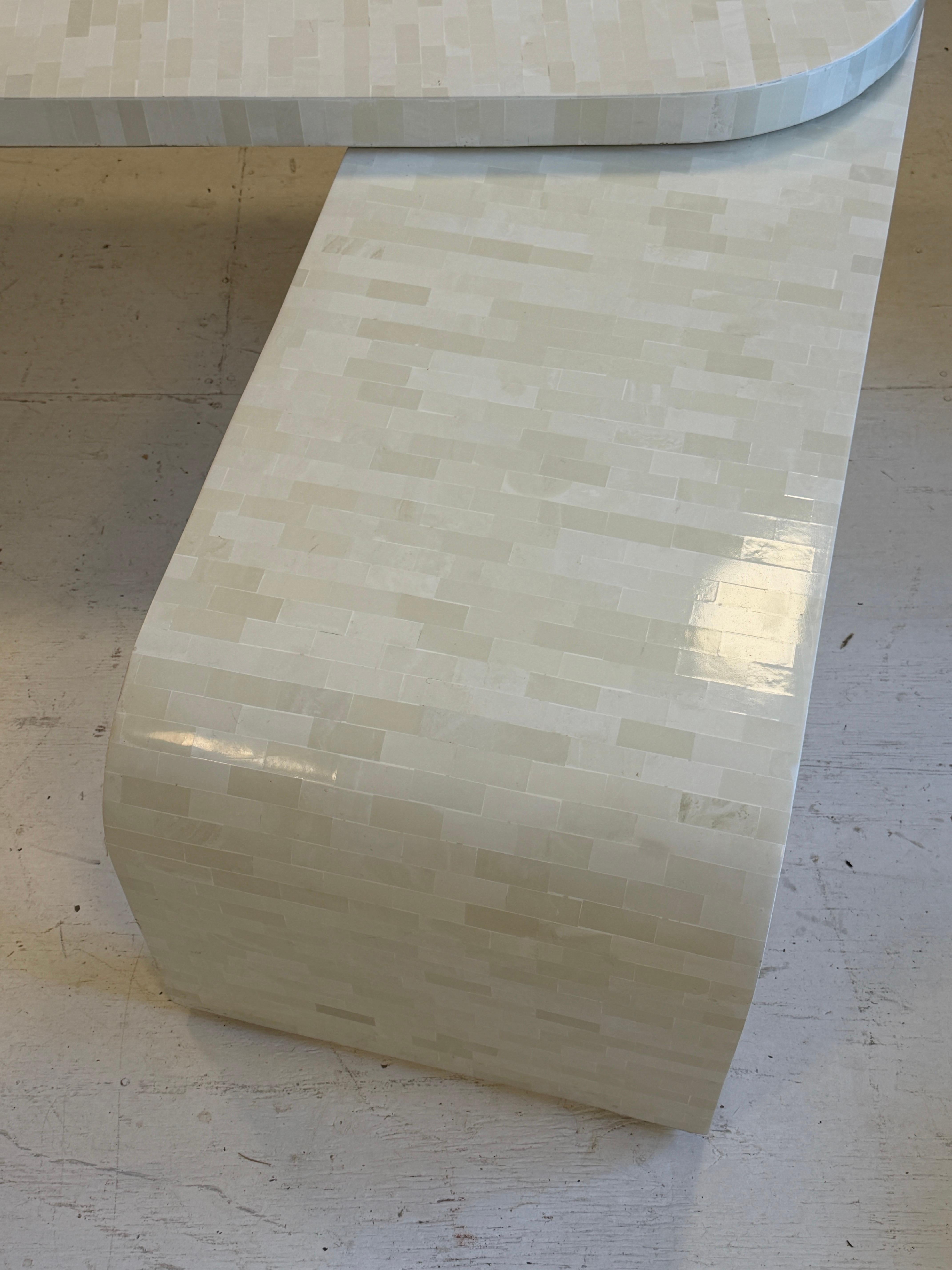 Both ‘wings’ on the table conceal rolling wheels, can be moved in any direction from the round center base. Made of tiled stone, and finished with a smooth finish. 

At the very longest end to end in a straight line configuration it’s 78” long.