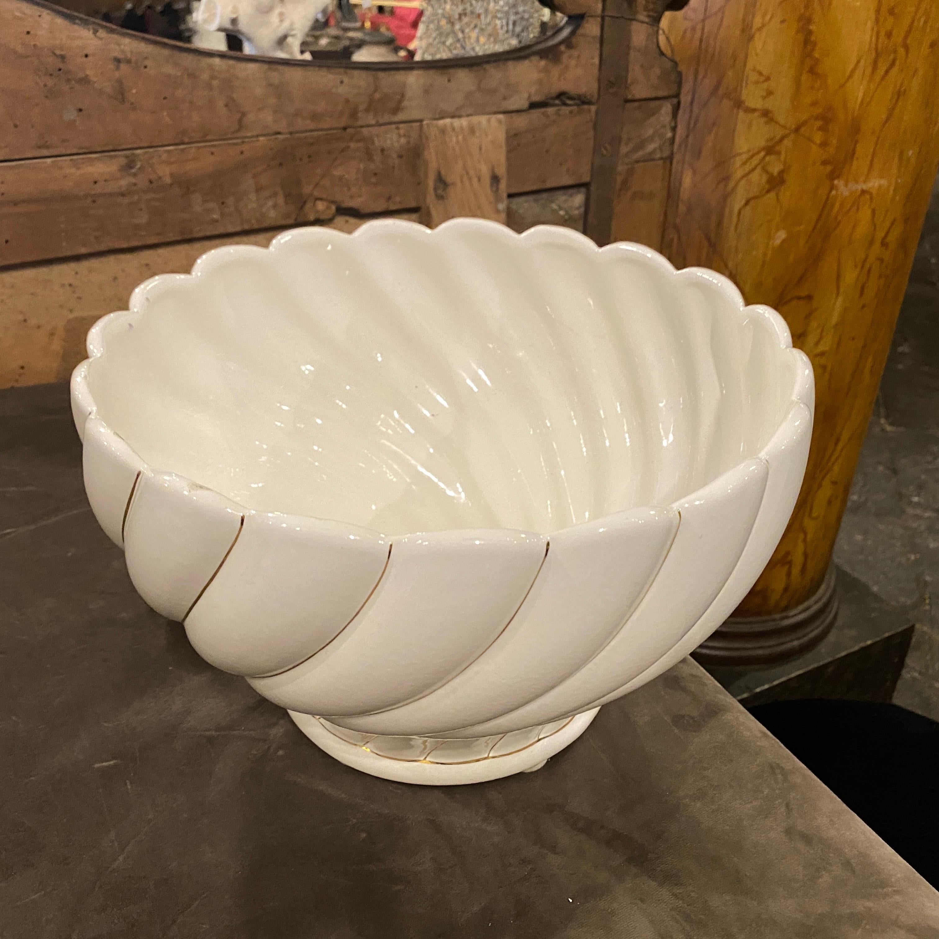 It's a stylish white and gold porcelain centerpiece designed and manufactured in Italy in the Seventies by Tommaso Barbi, marked on the bottom. The item is in good conditions. The bowl embodies the era's design principles, combining simplicity with