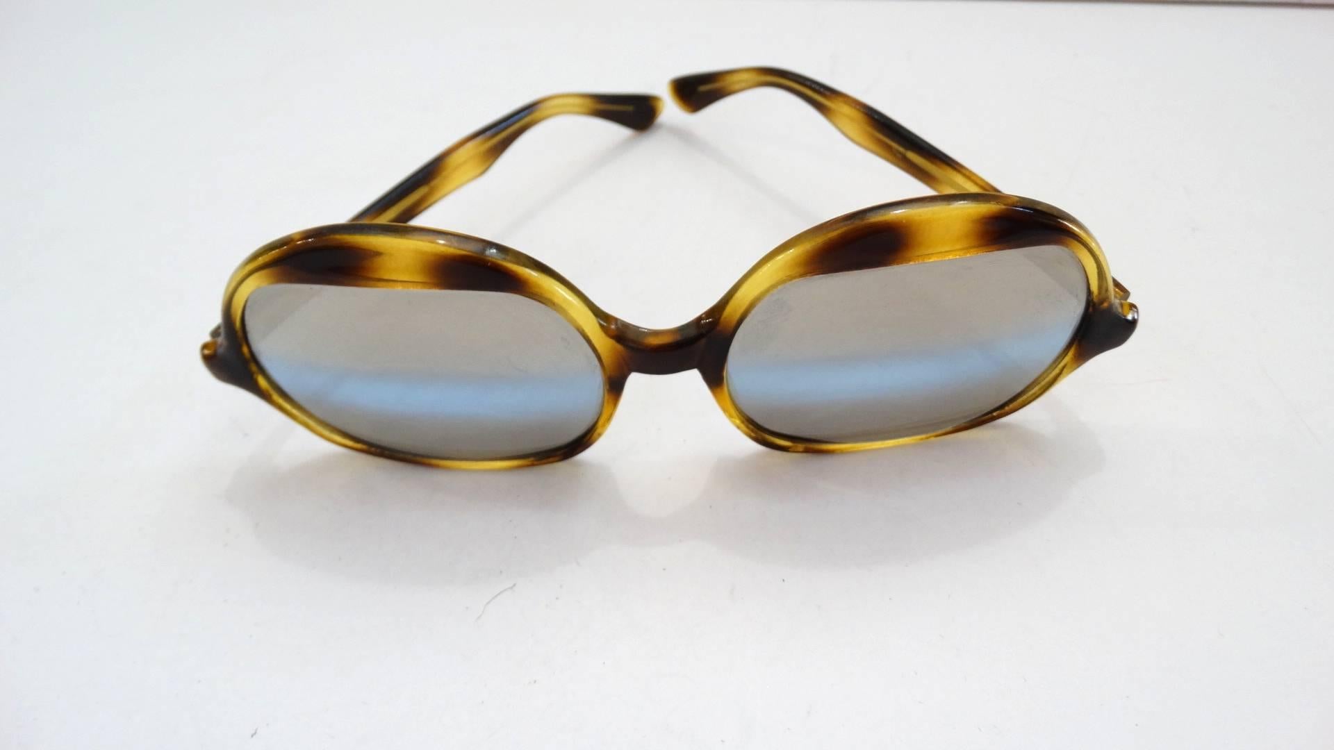Channel your inner Elton John with our amazing 1970s tortoise oversized sunglasses! Made of a yellow and brown spotted tortoise enamel. Unique shaped lenses, rounded at the top and flat on the bottom. Grey colored lenses with bluish grey stripe