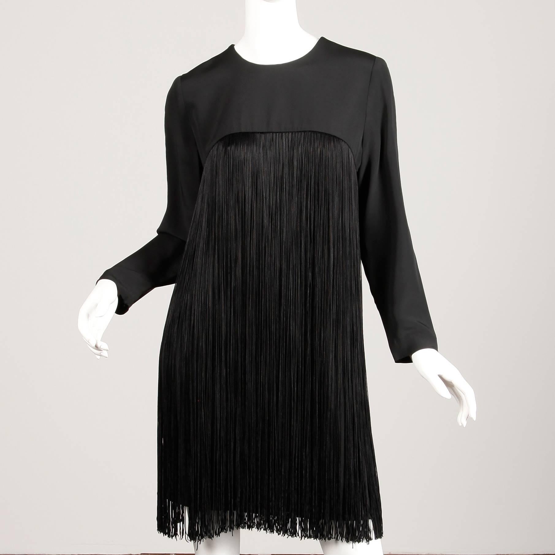 Gorgeous vintage black cocktail dress with long fringe by Travilla. Fully lined with rear zip closure and snap closure at wrists. The marked size is 10, but the dress fits like a modern size small-medium. The bust measures 36