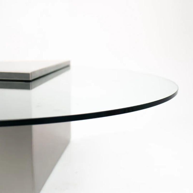 This is a Triform Cantilevered Coffee Table, designed by J. Wade Beam in 1970 for Breuton. It is formed of a satin stainless steel triangular base with pencil edges throughout, and a thick piece of intersecting cantilevered glass with 1/2