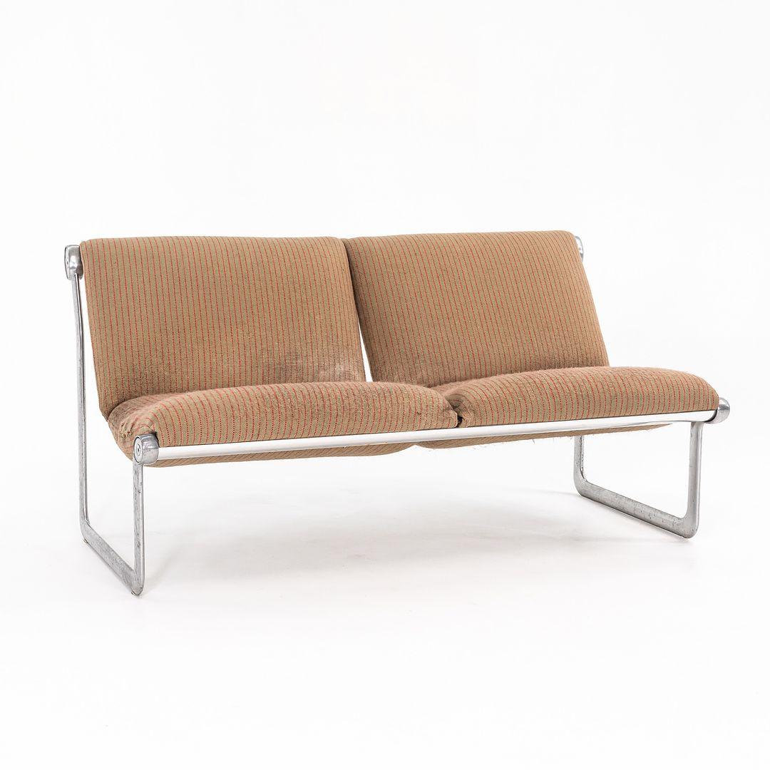 Si tratta di un divano a due posti disegnato da Bruce Hannah & Andrew Morrison per Knoll nel 1971. Presenta una struttura in acciaio fuso lucidato e una seduta e uno schienale imbottiti. La tappezzeria è attualmente in materiale marrone a righe. 
 
