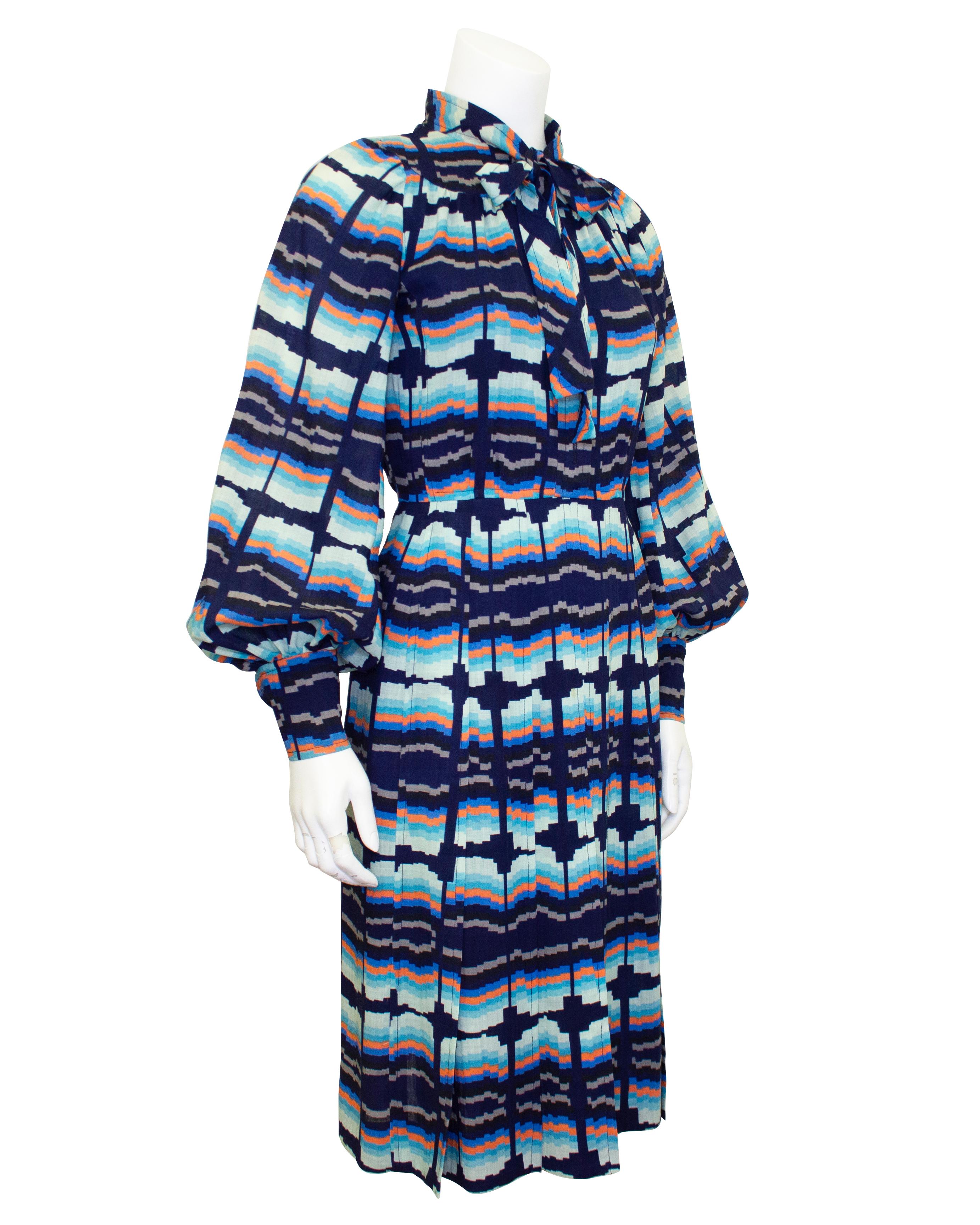 1970s Emanuel Ungaro cotton shirtdress. The dress features distorted horizontal stripes in shades of blue, orange and grey. Bishop sleeves and a thin pussy bow tie at the neck. Fitted at the waist, the skirt has inverted box pleats. A beautiful fall