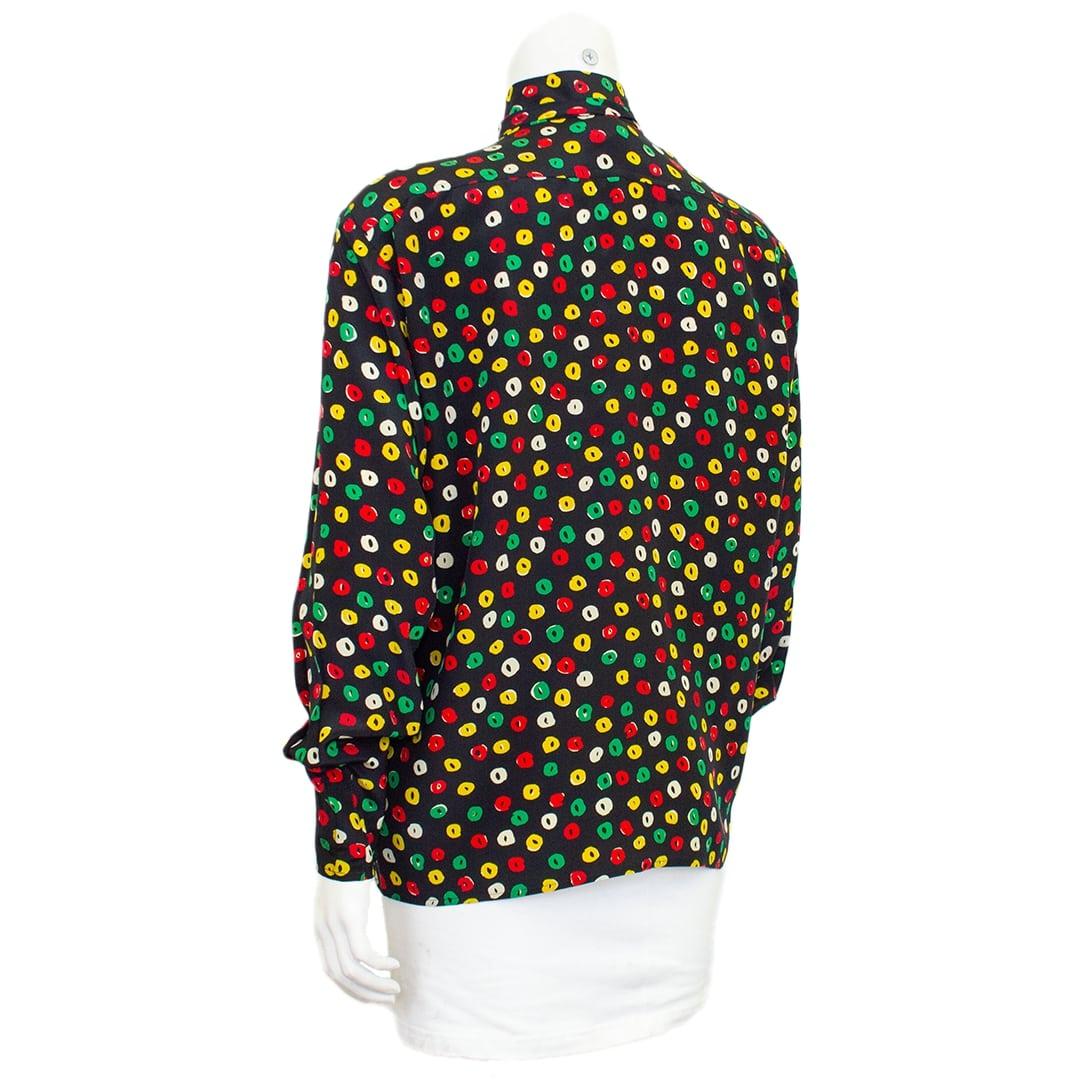 Zeitlose gemusterte Seidenbluse von Ungaro aus den 1970er Jahren mit Schleife und leicht gerafftem Ärmel. Schwarze Seide mit kellygrünen, gelben und roten handgemalten Effektpunkten. Der Look ist klassisch und passt gut zu einem Blazer, zu Jeans
