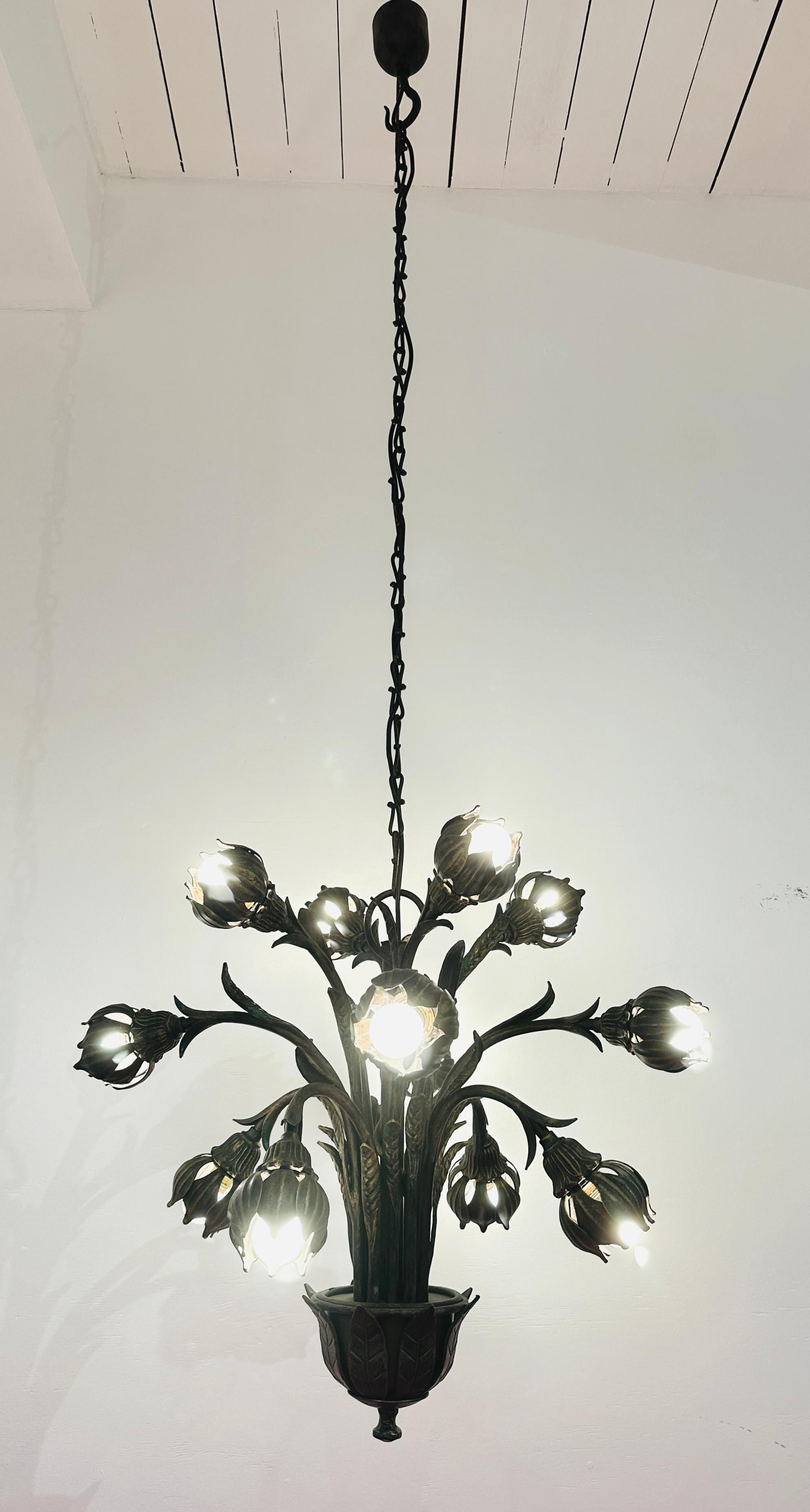 Lustre inhabituel en fonte allemande avec un effet faux bronze comprenant 12 bras individuels contorsionnés pour créer l'apparence d'une plante étrange telle qu'un Triffid.  Chaque ampoule ronde est entourée d'une fleur aux pétales individuels.  La