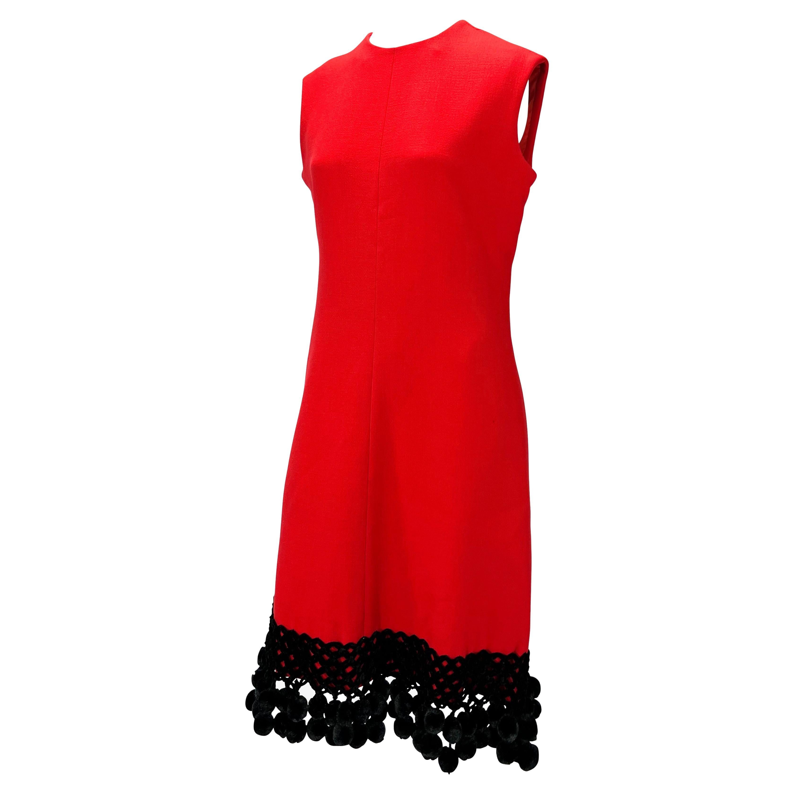 Te presentamos un impresionante vestido rojo y negro de Valentino Garavani. De los años 70, este vestido sin mangas de lana roja vibrante tiene escote redondo y se completa con un detalle de pompón negro en el bajo. Perfectamente moderno, este