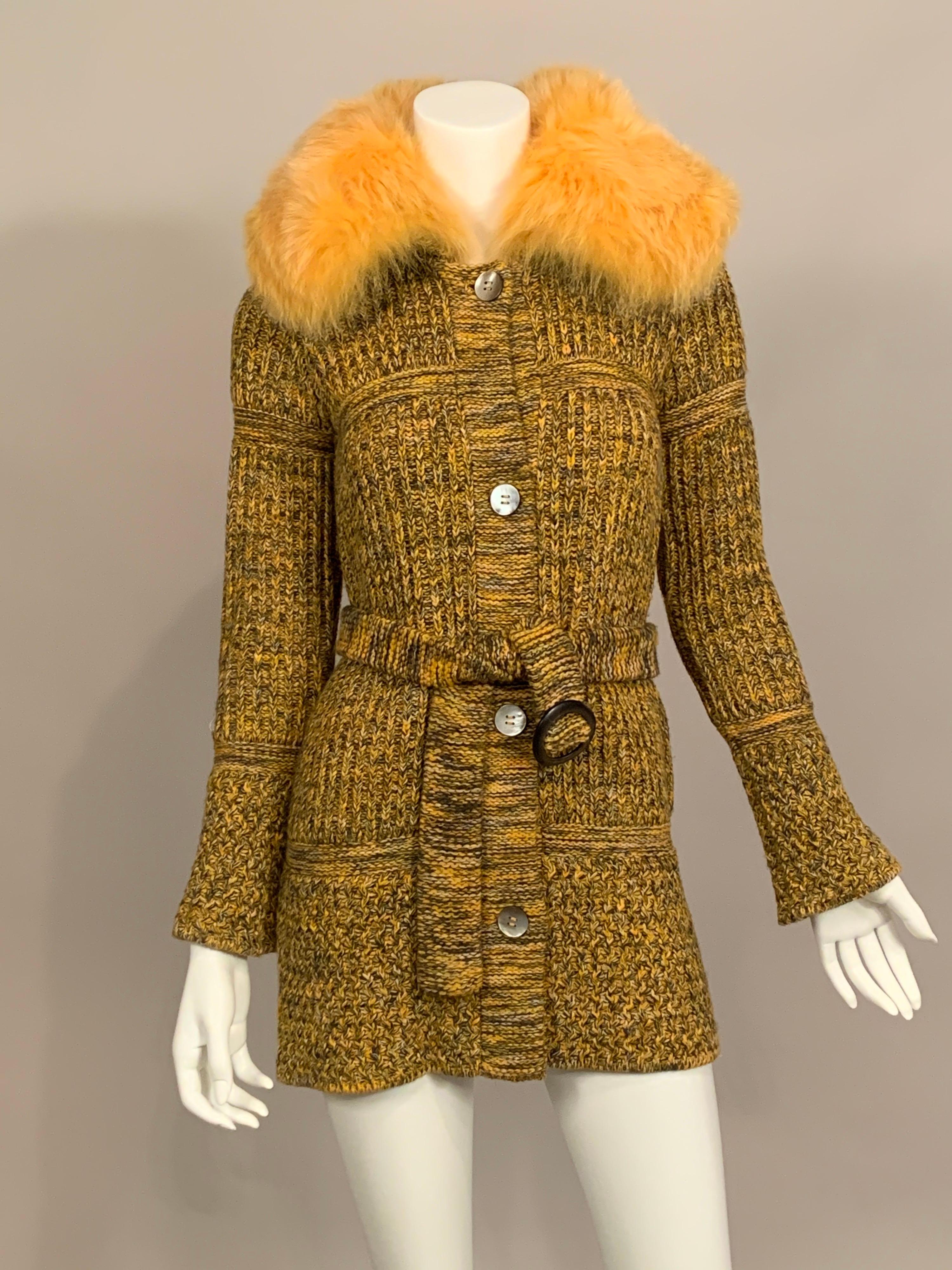 Knit from a multicolor yarn in shades of yellow, orange, charcoal, black and white this sweater includes several different knit patterns in large panels creating an interesting modern design.  It has a fluffy yellow/orange fox collar and four grey