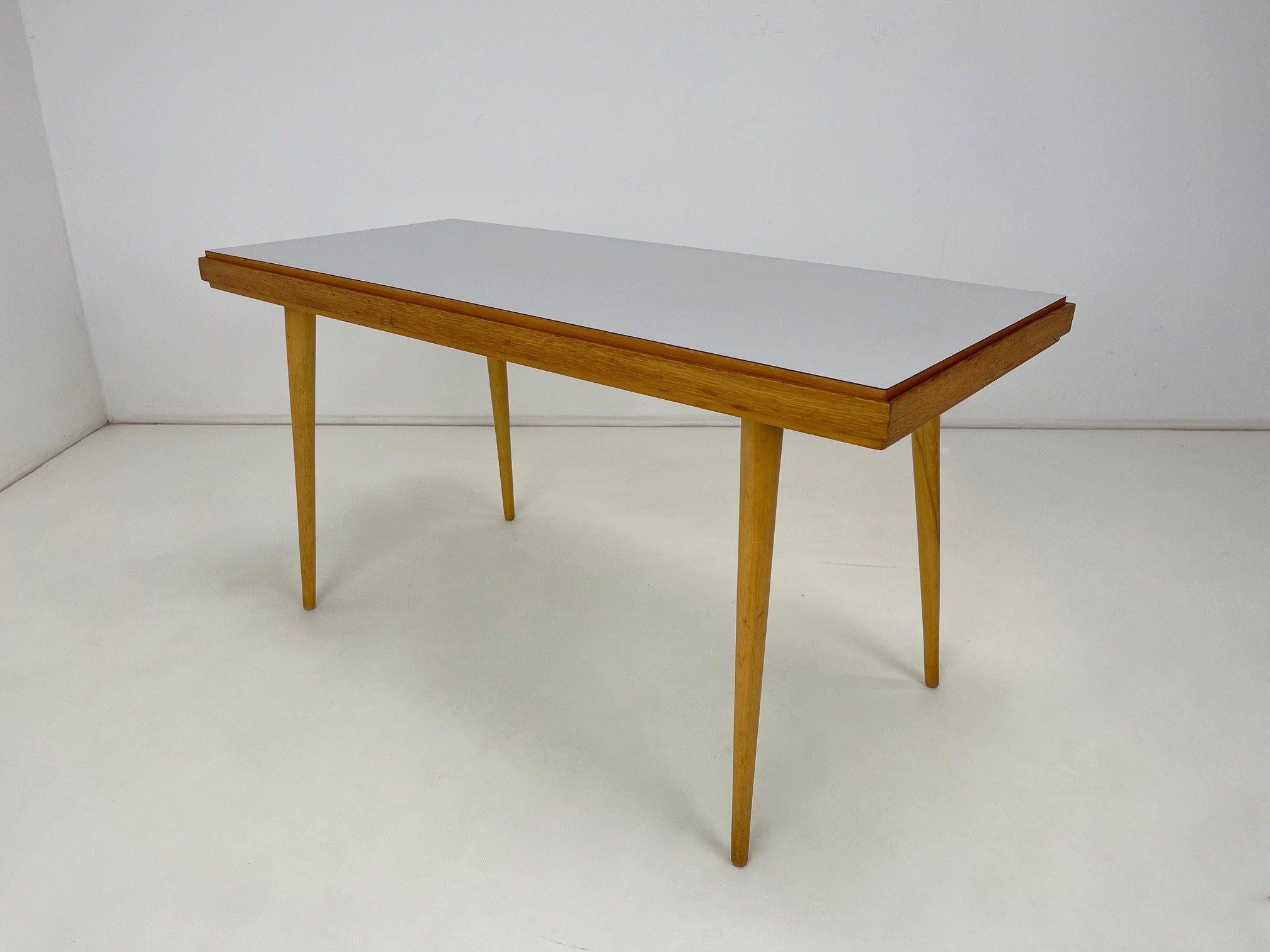 Vintage coffee table from former Czechoslovakia. The top can be flipped with yellow formica on one side and white on the other.