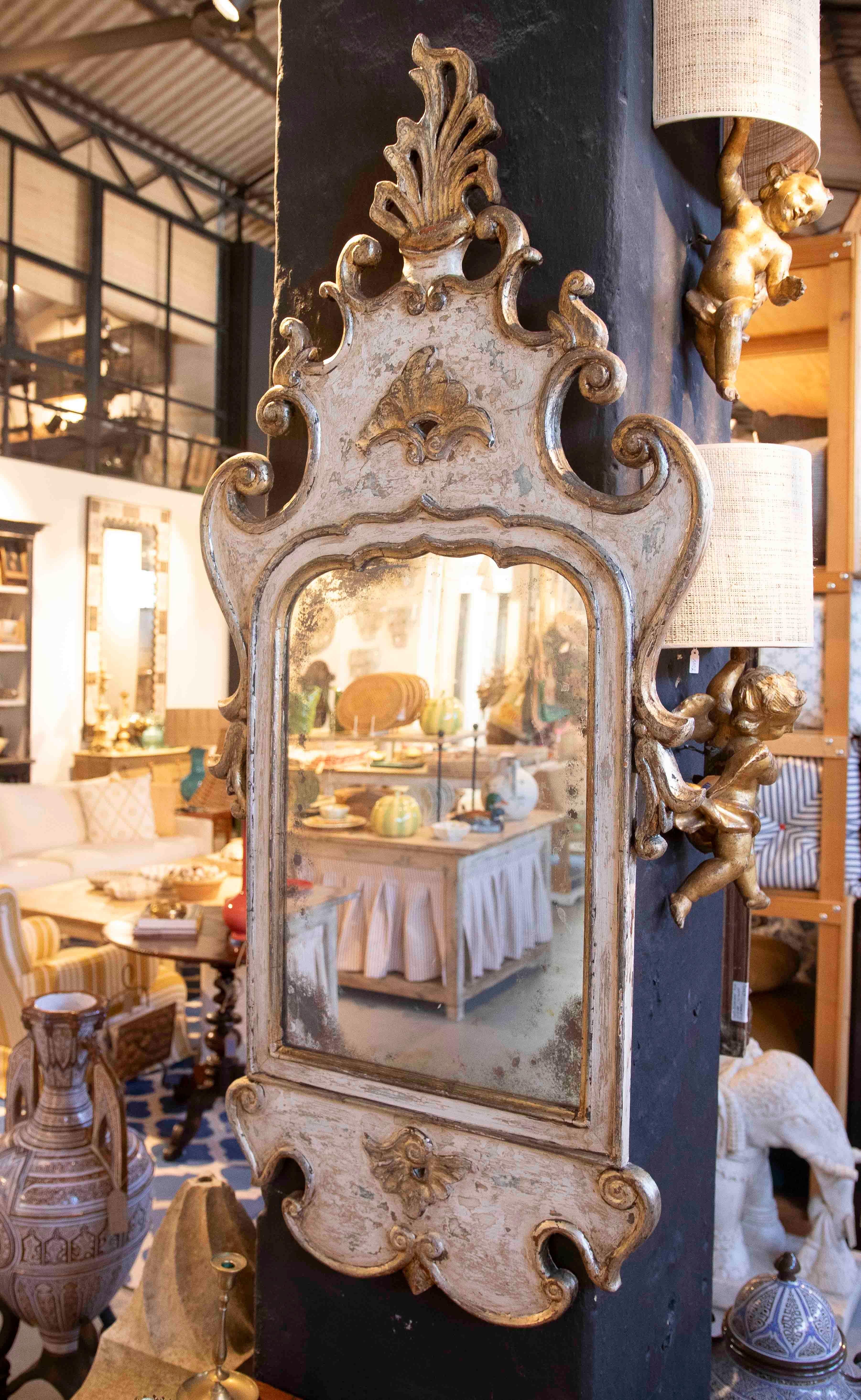 Elegant vintage Venetian mirror with a richly ornate carved wooden frame, finished in gilt leaf with an aged patina. The glass shows natural wear, adding authenticity and character to the piece.

The curved details, scrolls, and plant motifs make it