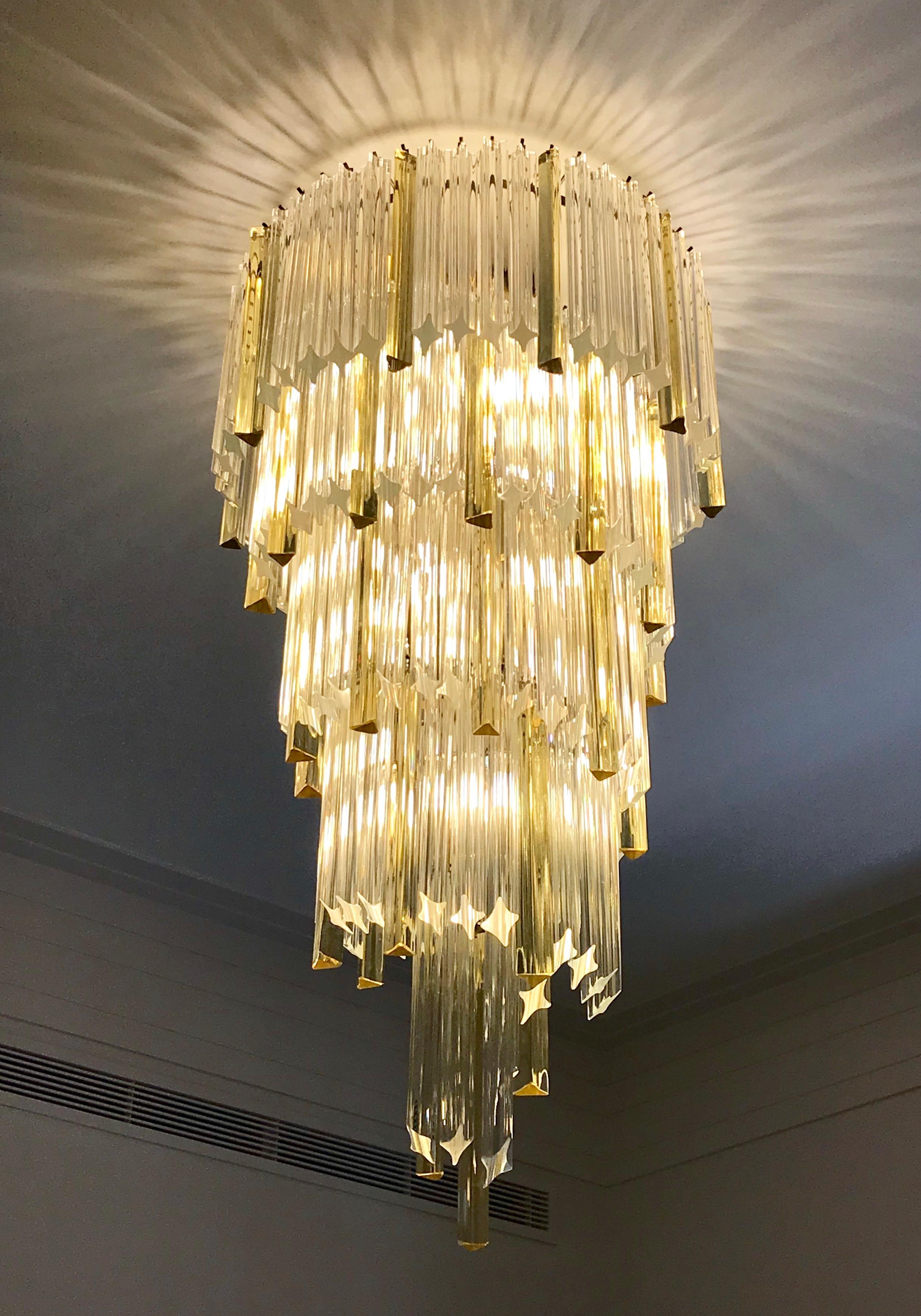 Midcentury design organic chandelier, entirely handcrafted in Italy, an iconic design by Venini. The handmade brass structure supports blown Murano glass elements of triangular section, called triedri, in crystal clear and amber color in an