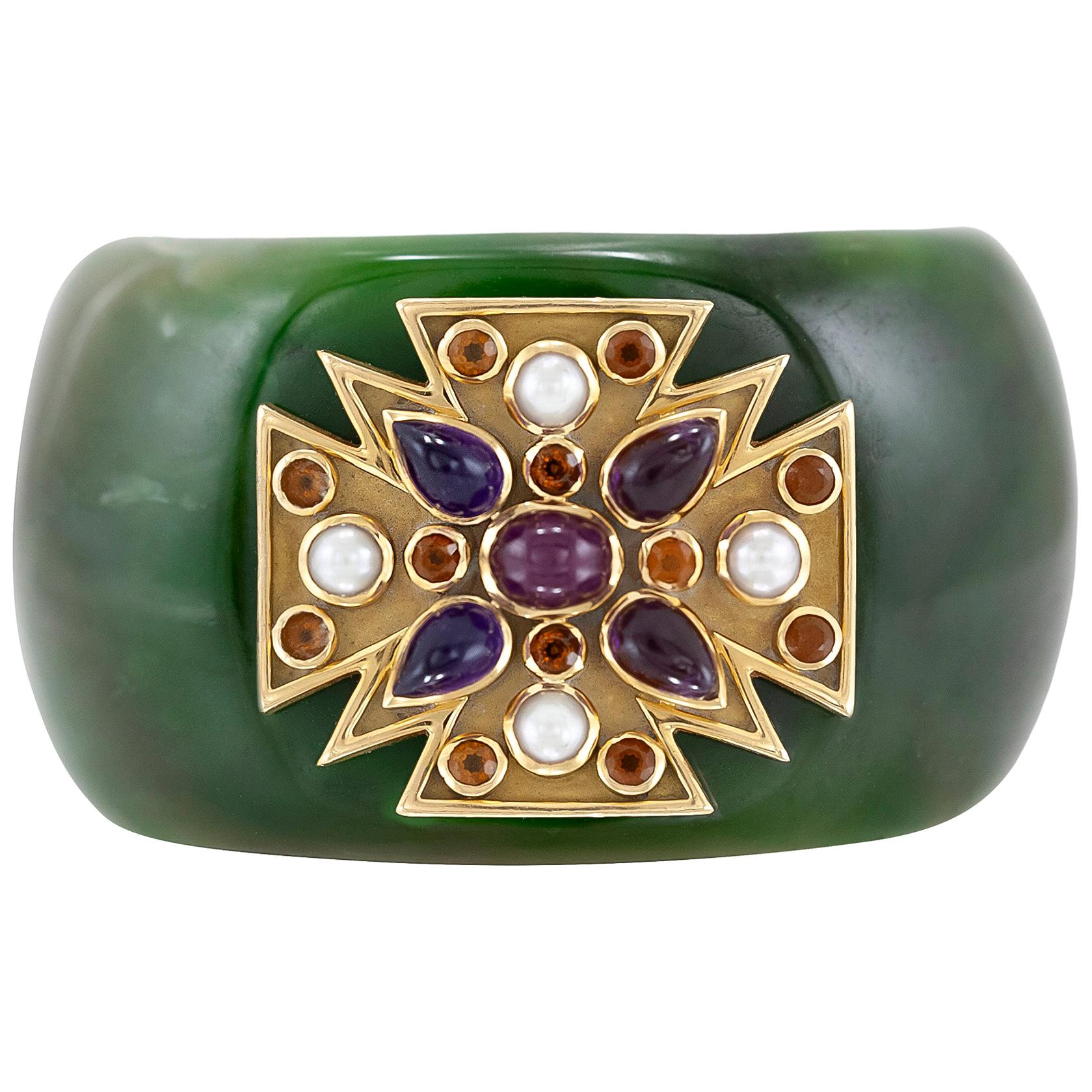 Pair of carved green jade cuffs featuring a 18K yellow gold Maltese crosses with a cabochon ruby at the center surrounded by pear-shaped cabochon amethysts, round-cut citrines and cultured pearls.
Signed by Verdura.
Comes with certificate from