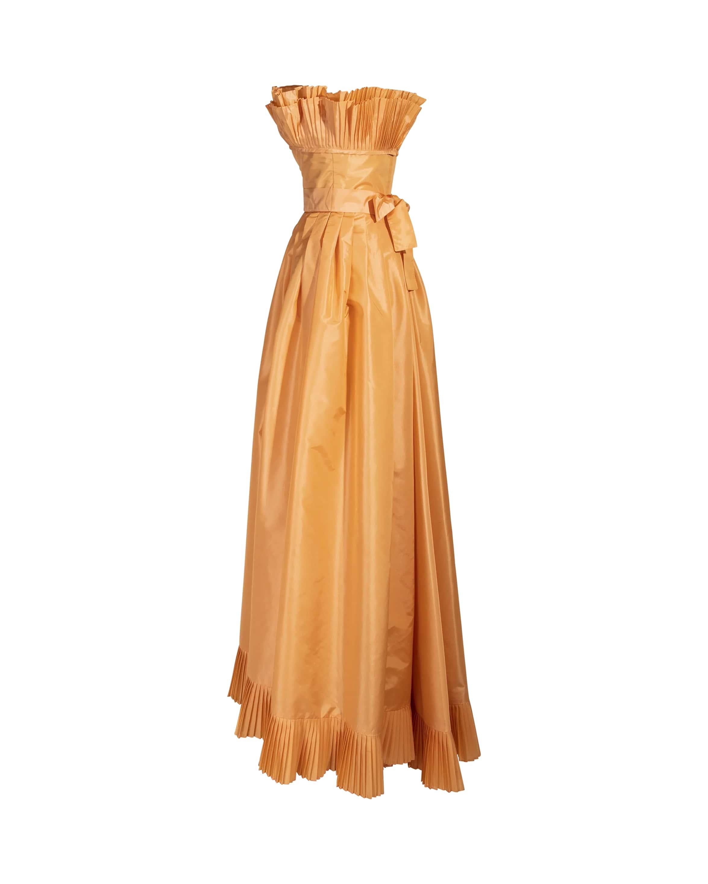 1970's Victor Costa orange iridescent taffeta strapless gown with ruffle trim. Fitted waist gown with built-in belt and ruffles at bust and hemline. Back zip closure. 
