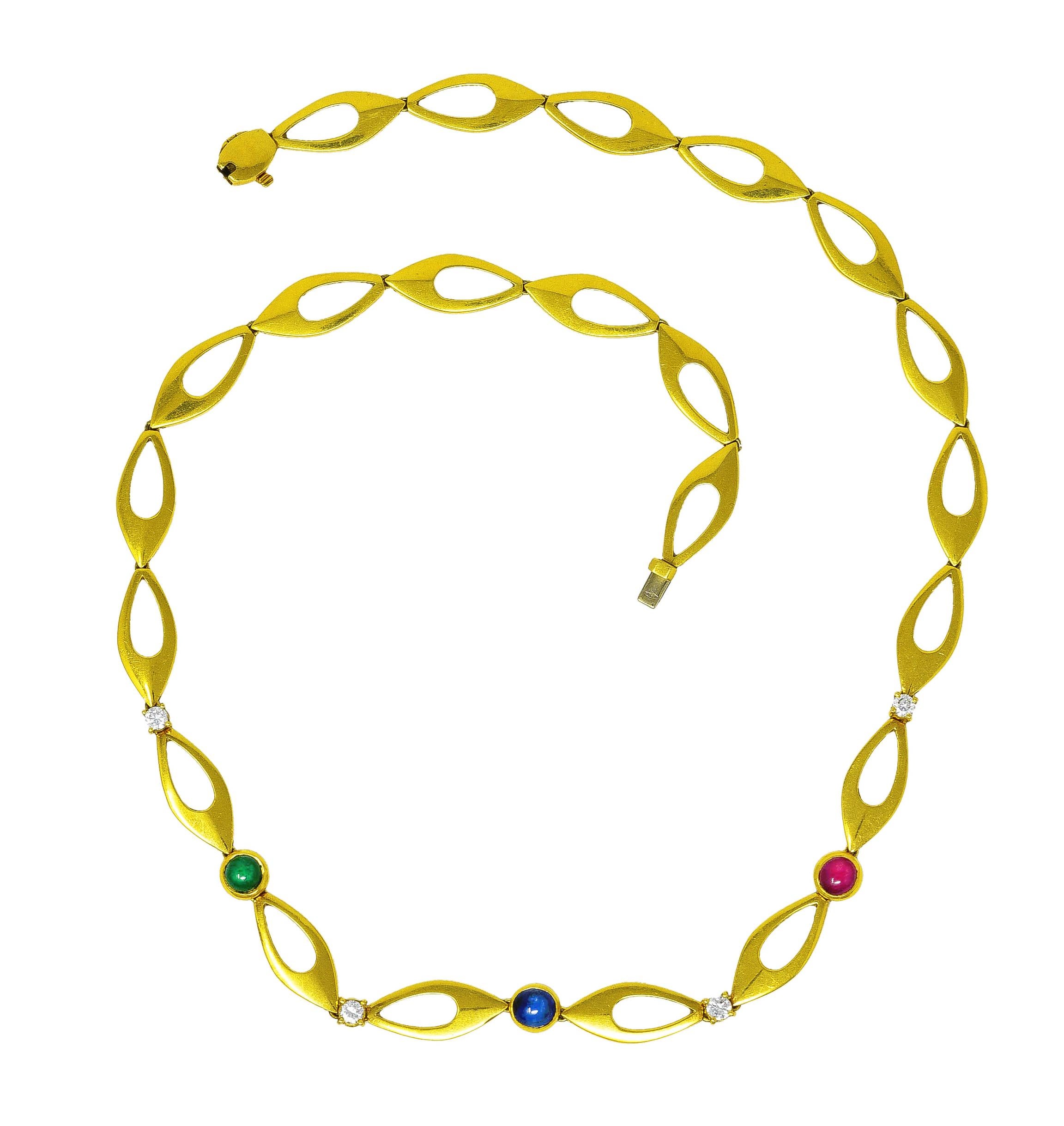 Necklace is comprised of asymmetrical ellipse style links alternating with gemstone stations. Featuring three bezel set cabochons of ruby, emerald, and a sapphire. Brightly colored and weighing collectively approximately 1.80 carats. With round