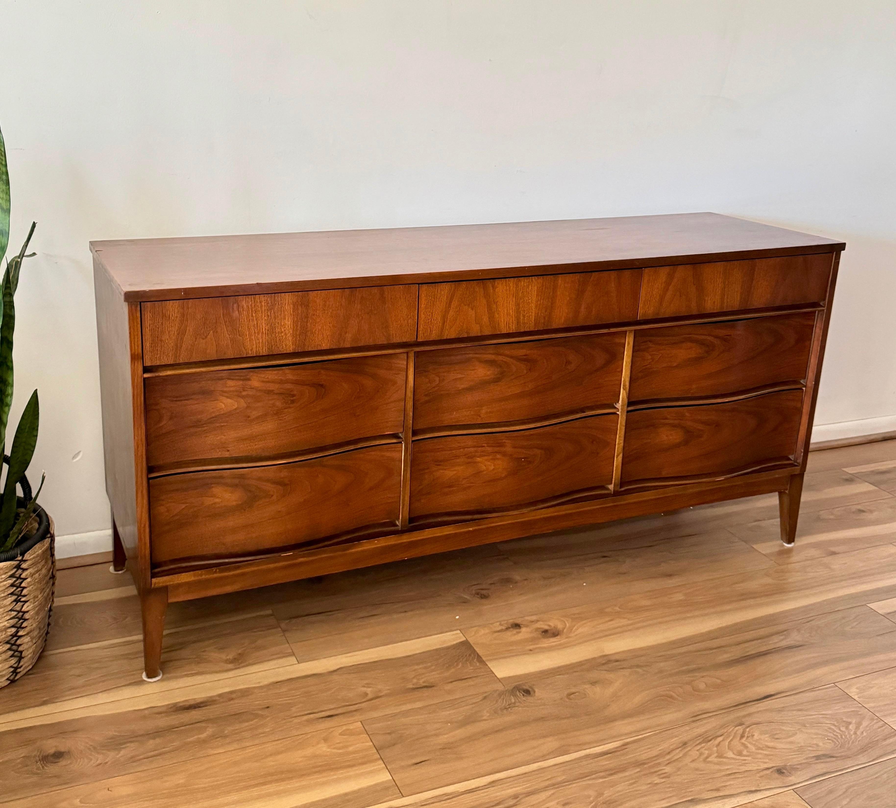1970s Vintage Mid Century Modern 9-Drawer Lowboy Dresser showcases a refined aesthetic, blending timeless design with functional craftsmanship. Its sleek silhouette is complemented by a thoughtfully curated curvy drawer arrangement, offering both