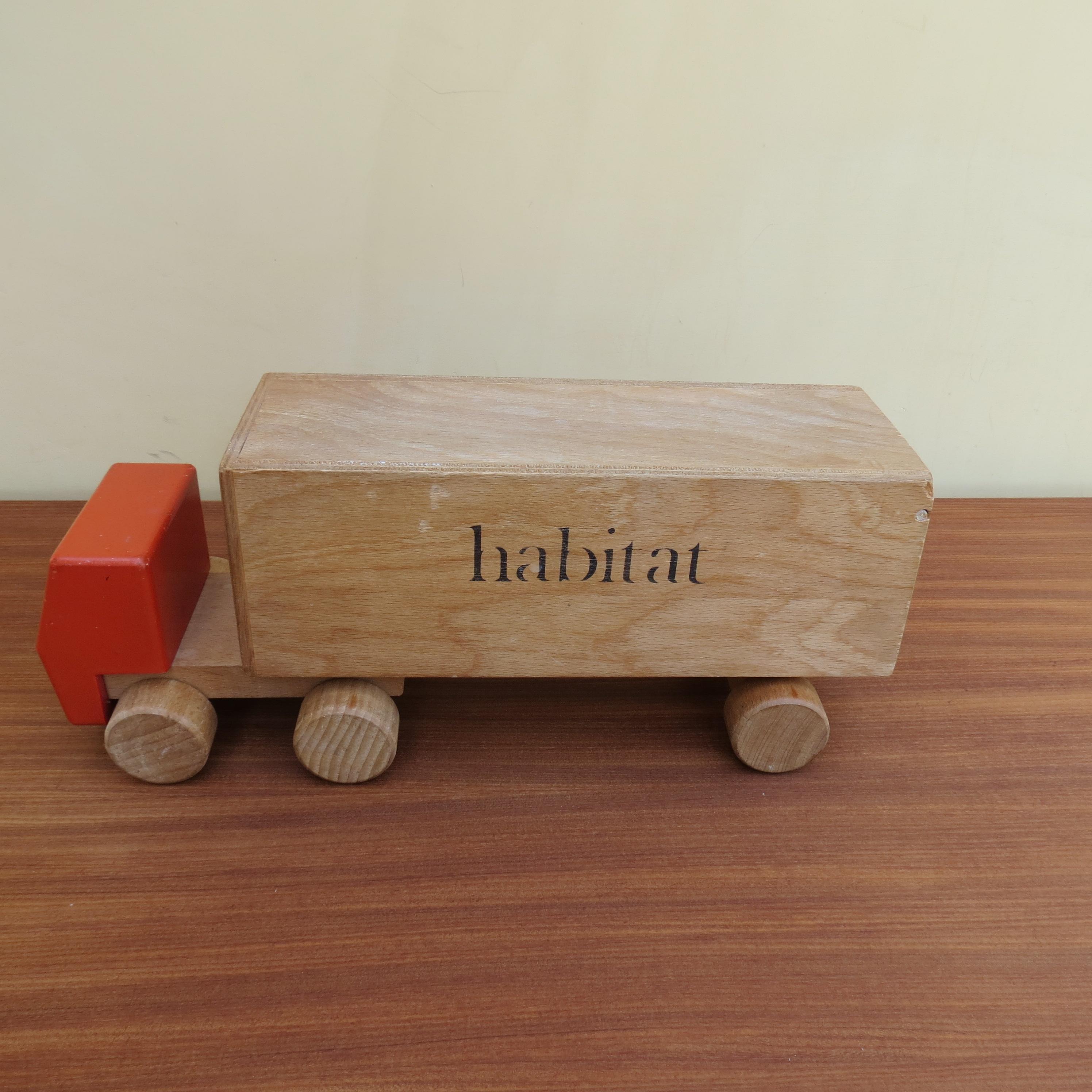 A wonderful toy lorry used for advertising Habitat. Dates from the 1970s. Made from wood and plywood. Painted wooden cab with pivoting trailer with opening tailgate. In good vintage condition, stamped Habitat to the side of the lorry. Stamped Made
