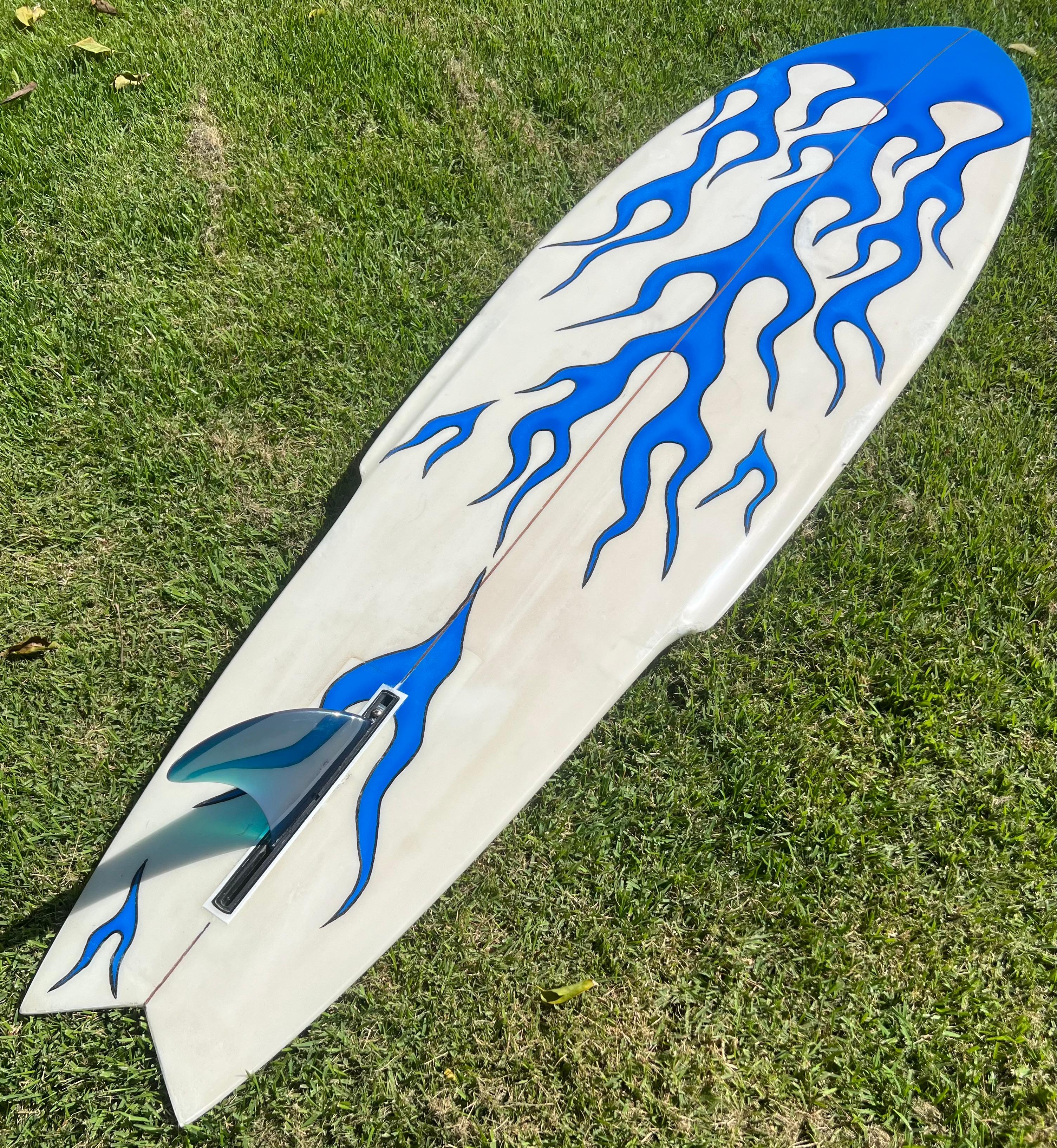 Vintage 1970s Aipa Wave Crest Hawaii surfboard. Features striking blue airbrushed flames design with pinlines and matching blue single fin. A remarkable example of Ben Aipa’s famous Sting surfboard design. The Sting shape was the first winged
