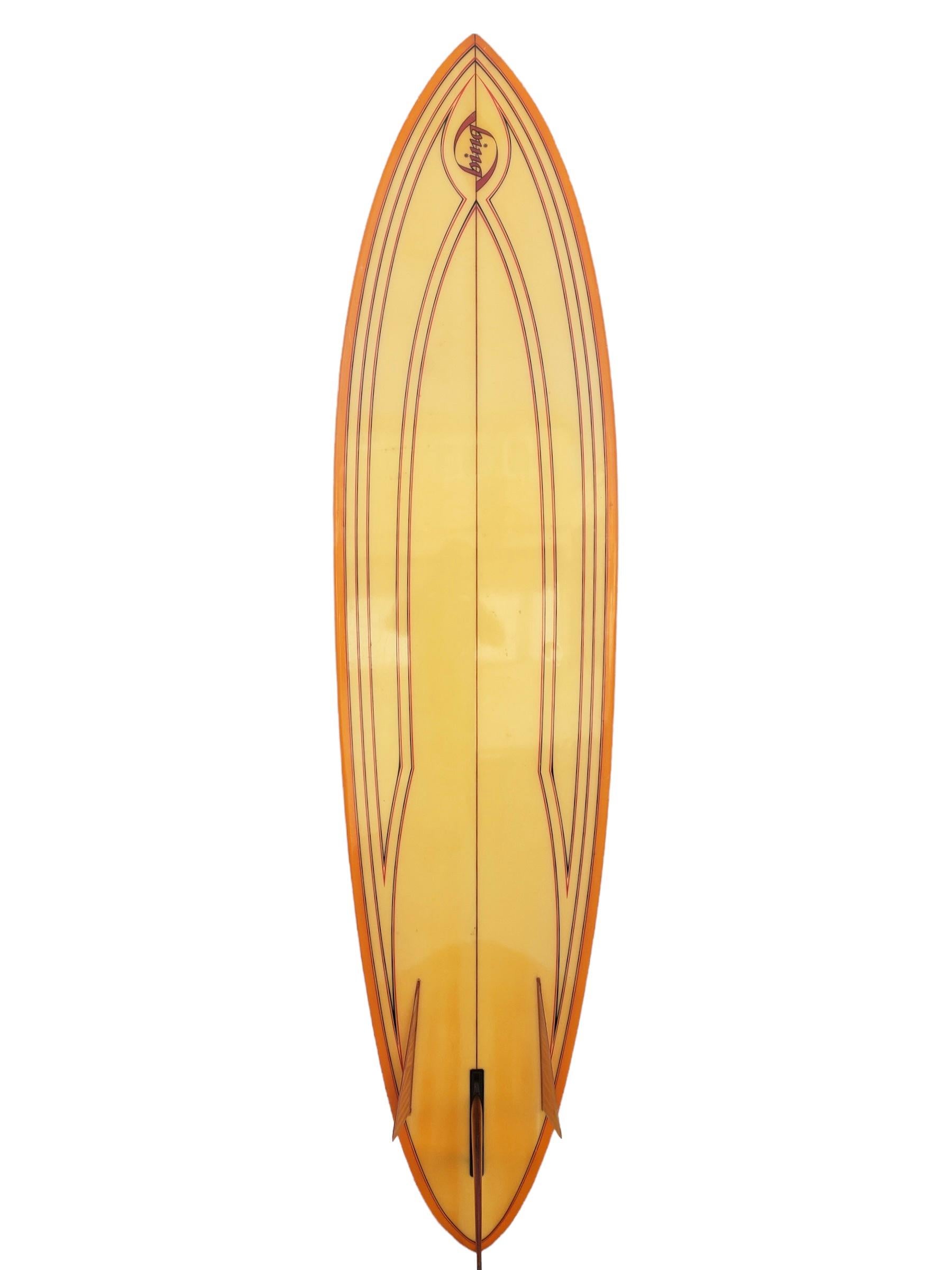 Early-mid 1970s Bing Surfboards 7’6 Bonzer shaped by Mike Eaton. Features a beautiful orange tinted deck/rails with intricate pinstriped bottom complimented by amber colored fins. A remarkable example of a well preserved 1970s Bing Bonzer surfboard.