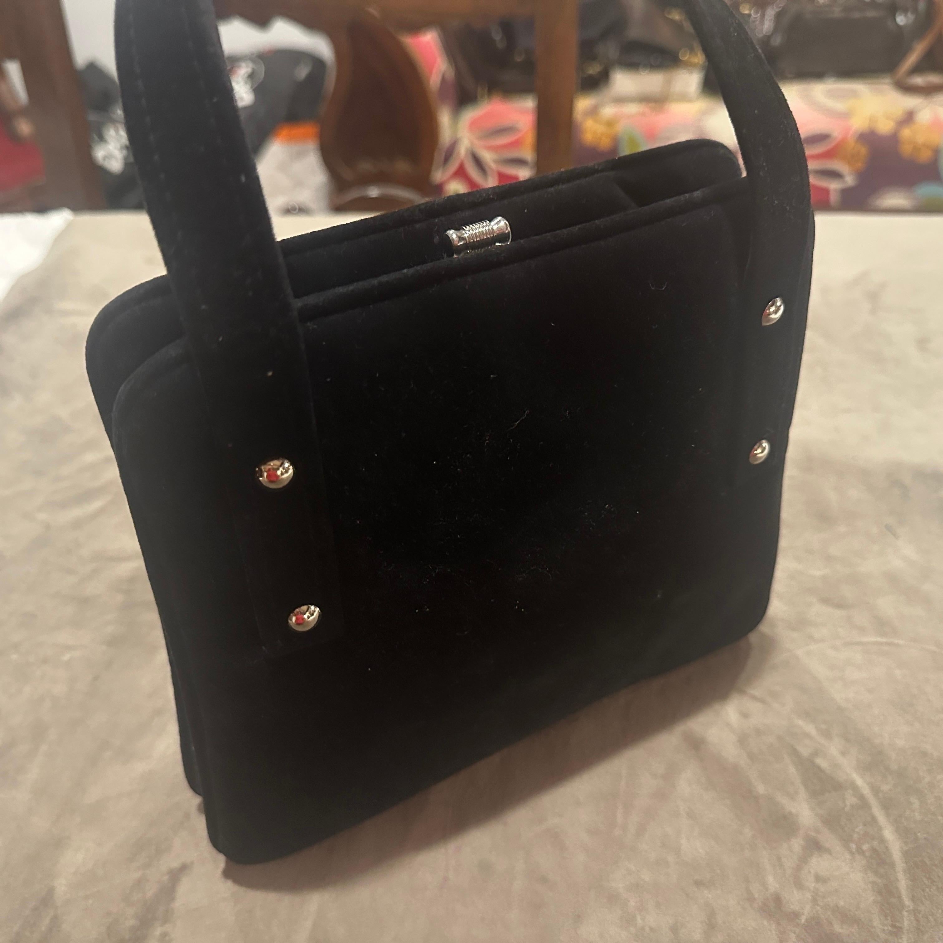 Ce sac à main vintage est un superbe exemple du glamour italien des années 1970. Il associe un daim noir somptueux à un métal argenté élégant pour un contraste saisissant et sophistiqué. Le sac présente une silhouette structurée, caractéristique de