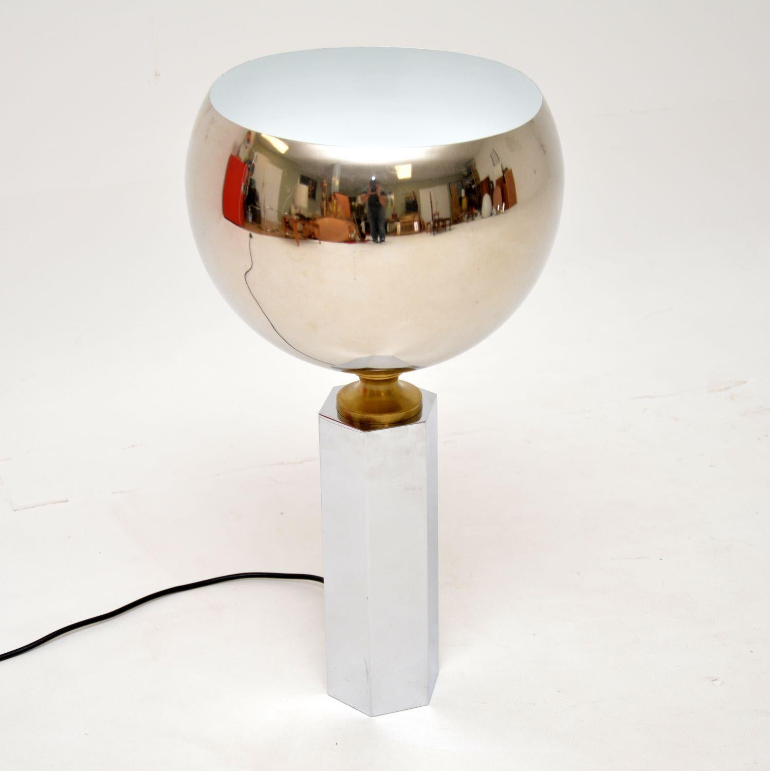 A stunning vintage chrome and brass table lamp, this was made in Europe, likely Italy or France, it dates from the 1970’s.

It is of great quality and has a very striking design. The spherical shade lights upwards, and is connected with a brass