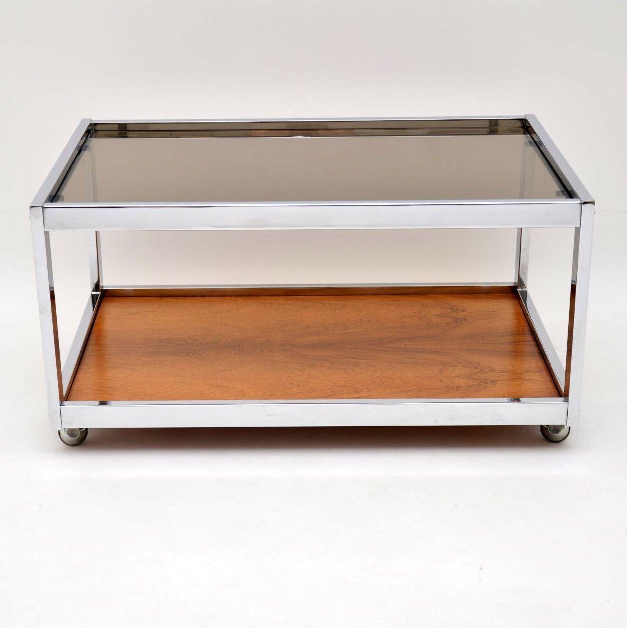 A stylish and very well made vintage coffee table with a chrome frame, wooden base and glass top. This was made by MDA Howard Miller Associates; it dates from the 1970s. This is in excellent condition for its age, it has been extremely well looked