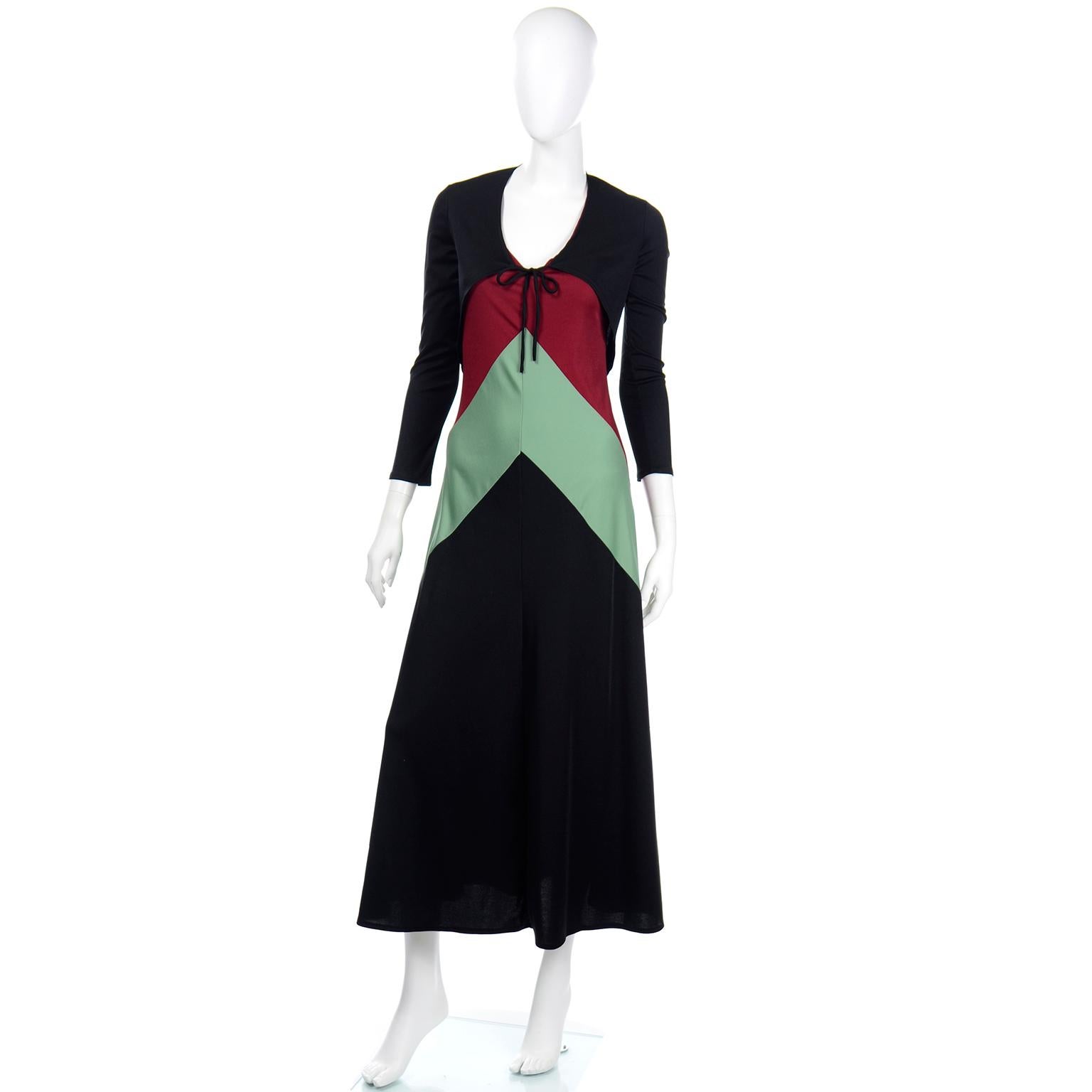This is such a fun 2 piece vintage jersey maxi tank dress from the 1970's with a coordinating black stretch bolero jacket. The dress is in a black jersey with pretty inverted V color blocking in shades of rusty red, sage green and black. The little