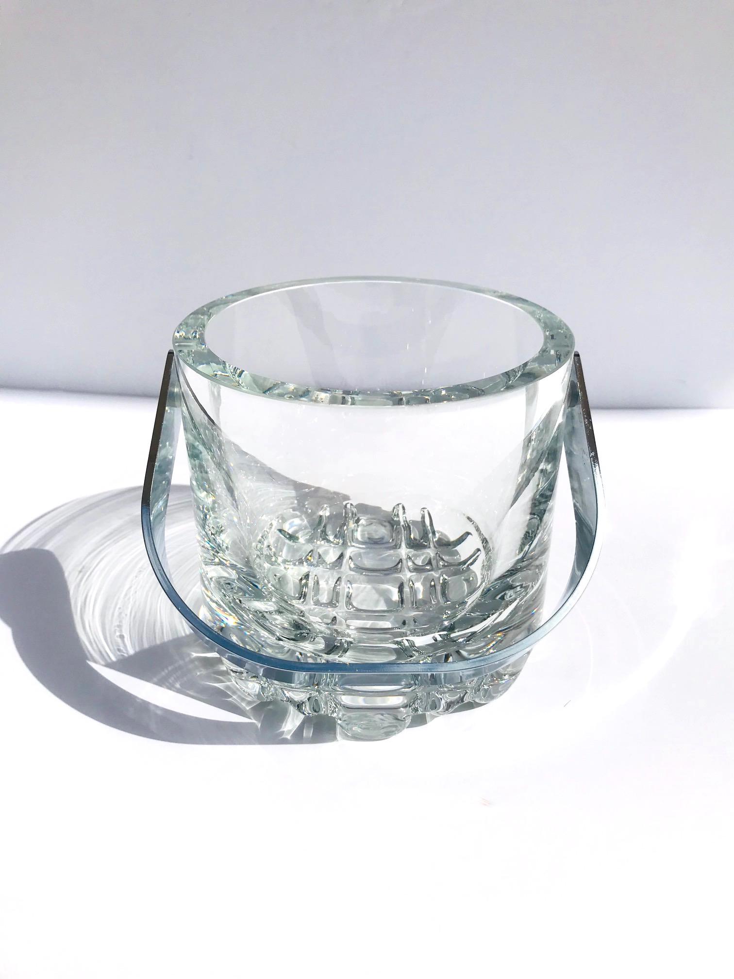 Exceptional Mid-Century Modern heavyweight crystal ice bucket. Heavy rounded edges with rock ice glass design along the base and with stainless steel handle. Makes a handsome addition to any barware set and can double as a wine cooler.