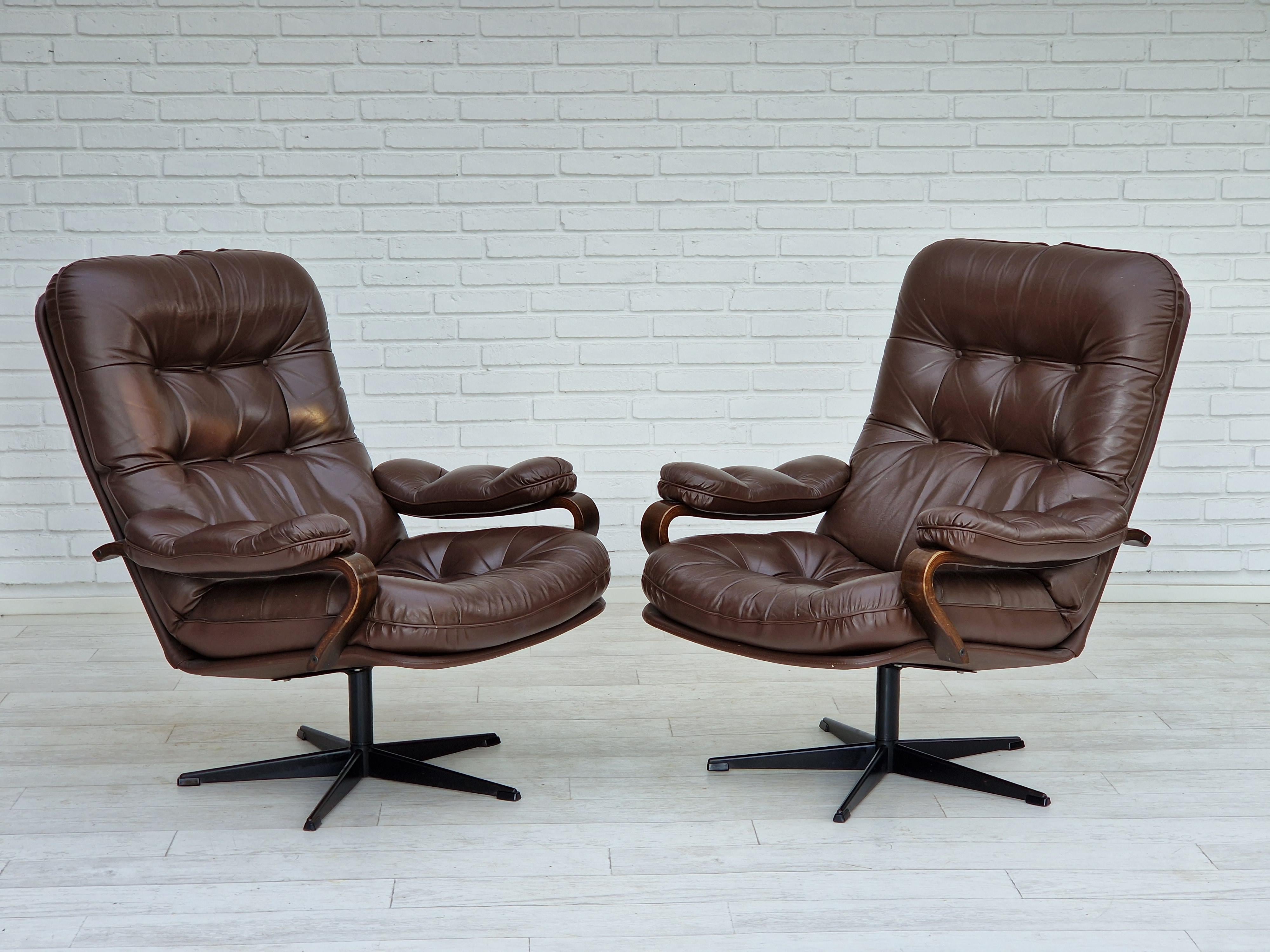 Années 1970, Design/One. Paire de fauteuils pivotants en cuir brun. Bon état : pas d'odeurs ni de taches. Pied d'acier.