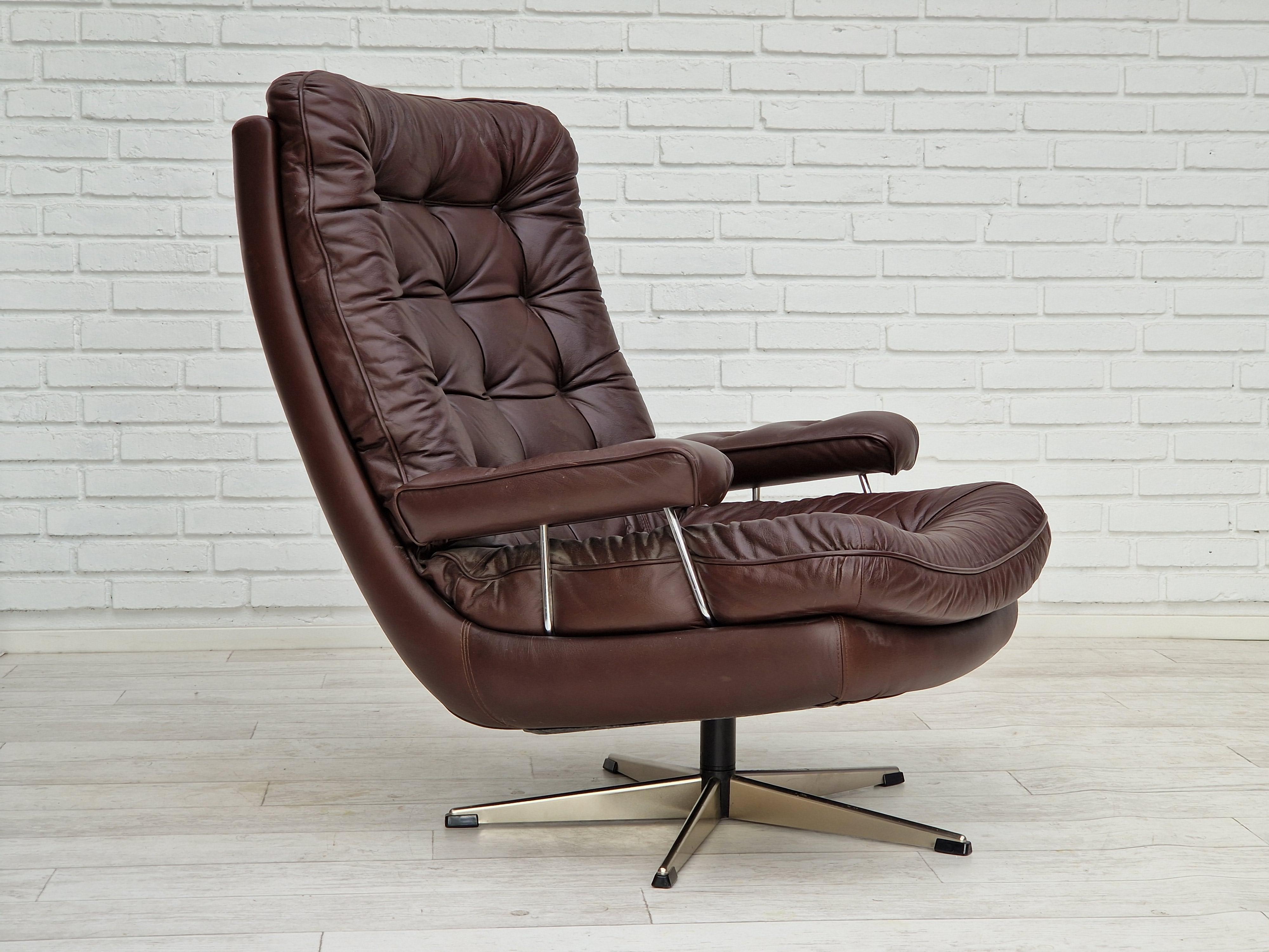 70s, Danish swivel armchair. Original upholstery in brown leather. Five-star base made of chrome steel. Made in about 1970 by Danish furniture manufacturer. Original very good condition. No smells, no stains.