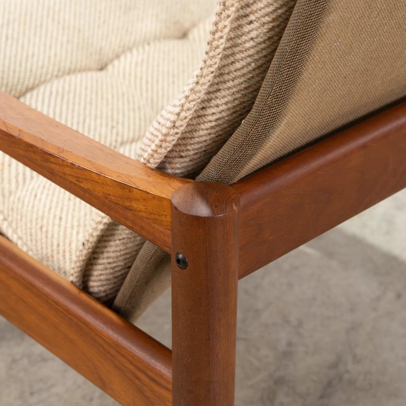 The vintage Danish high-back lounge chair by Domino Mobler is a quintessential piece of Scandinavian mid-century design. Crafted from solid teak. The high backrest is complemented by a plush, tufted cushion in textured beige upholstery. 
