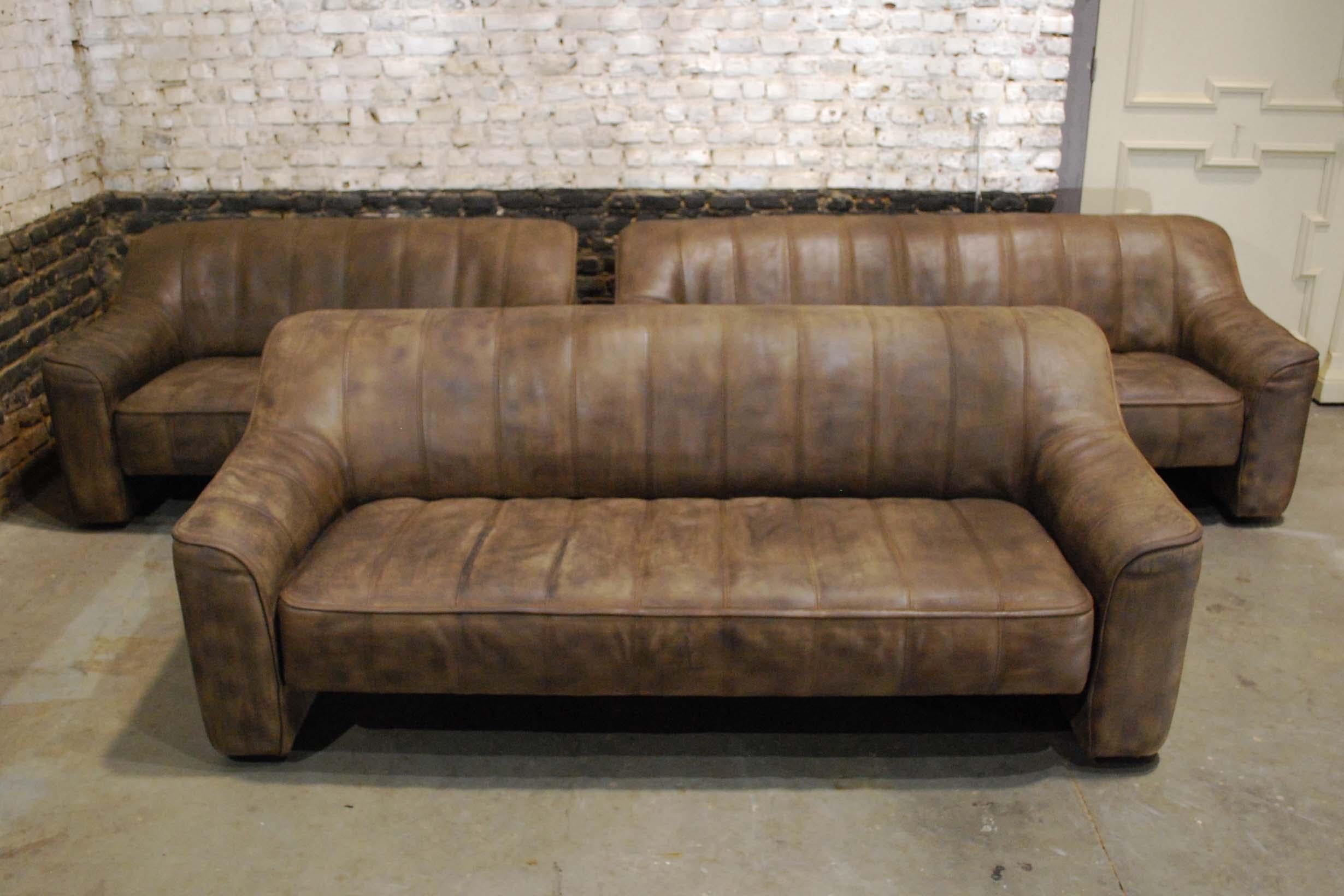 A beautiful Leather block style sofa set in walnut color with beautiful patina and vertical stitching, produced by De Sede, model 44. The softened edges and aged leather reference the organic and naturalist trend was seen in midcentury design. The