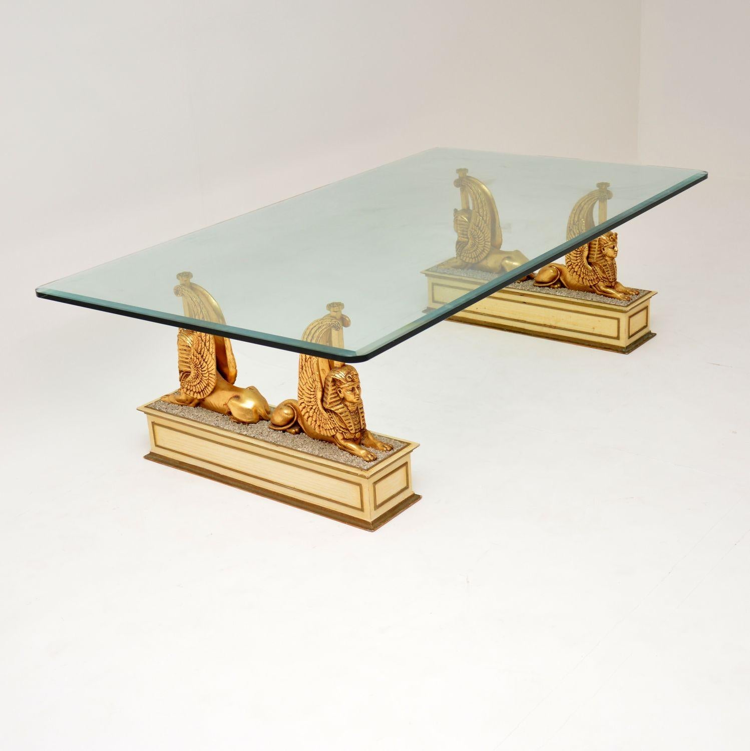 A stunning vintage coffee table, dating from the 1970s. This has a thick, bevelled glass top, supported by two beautiful pedestal bases. The bases are carved gilded wood in the images of Sphinxes. This is of super quality and is in excellent