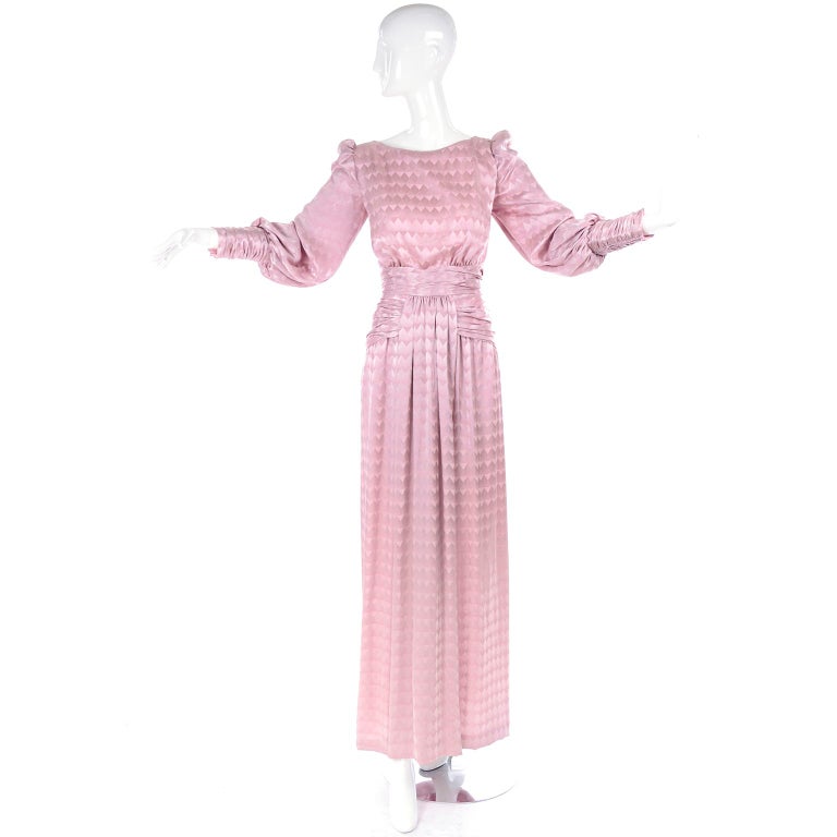 This is a lovely late 1970's long pink dress from Luis Estévez. The dress has gathered sleeves with a slight puff shoulder and ruching at the cuffs and from the waist through the top of the hips on the sides and in the back.  There are zippers on