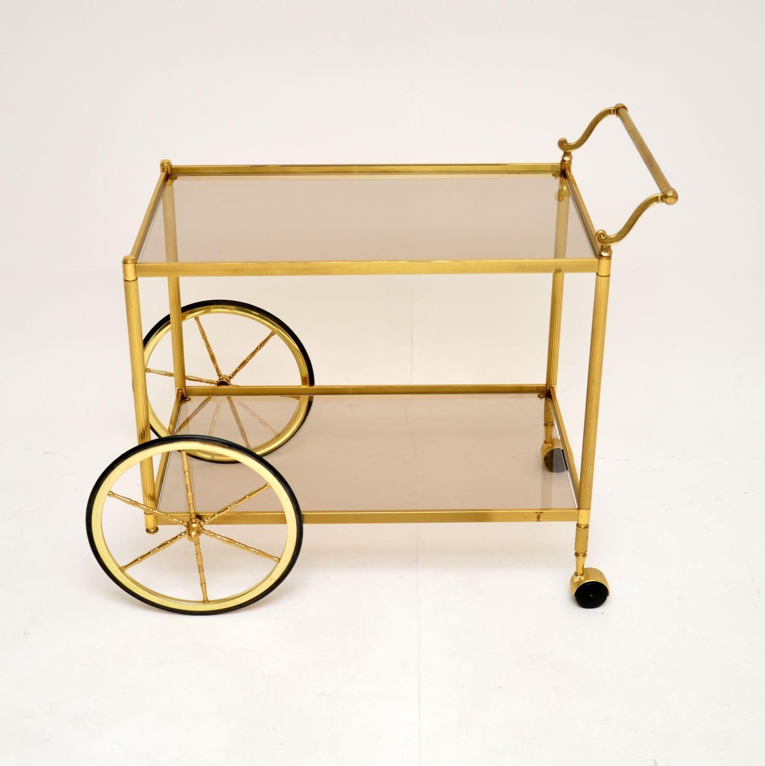 Chariot à boissons / chariot de bar en laiton et verre, très élégant et utile, datant des années 1970.

La qualité est fantastique, ce modèle est de grande taille et est magnifiquement conçu, avec des supports en laiton cannelé, une poignée en
