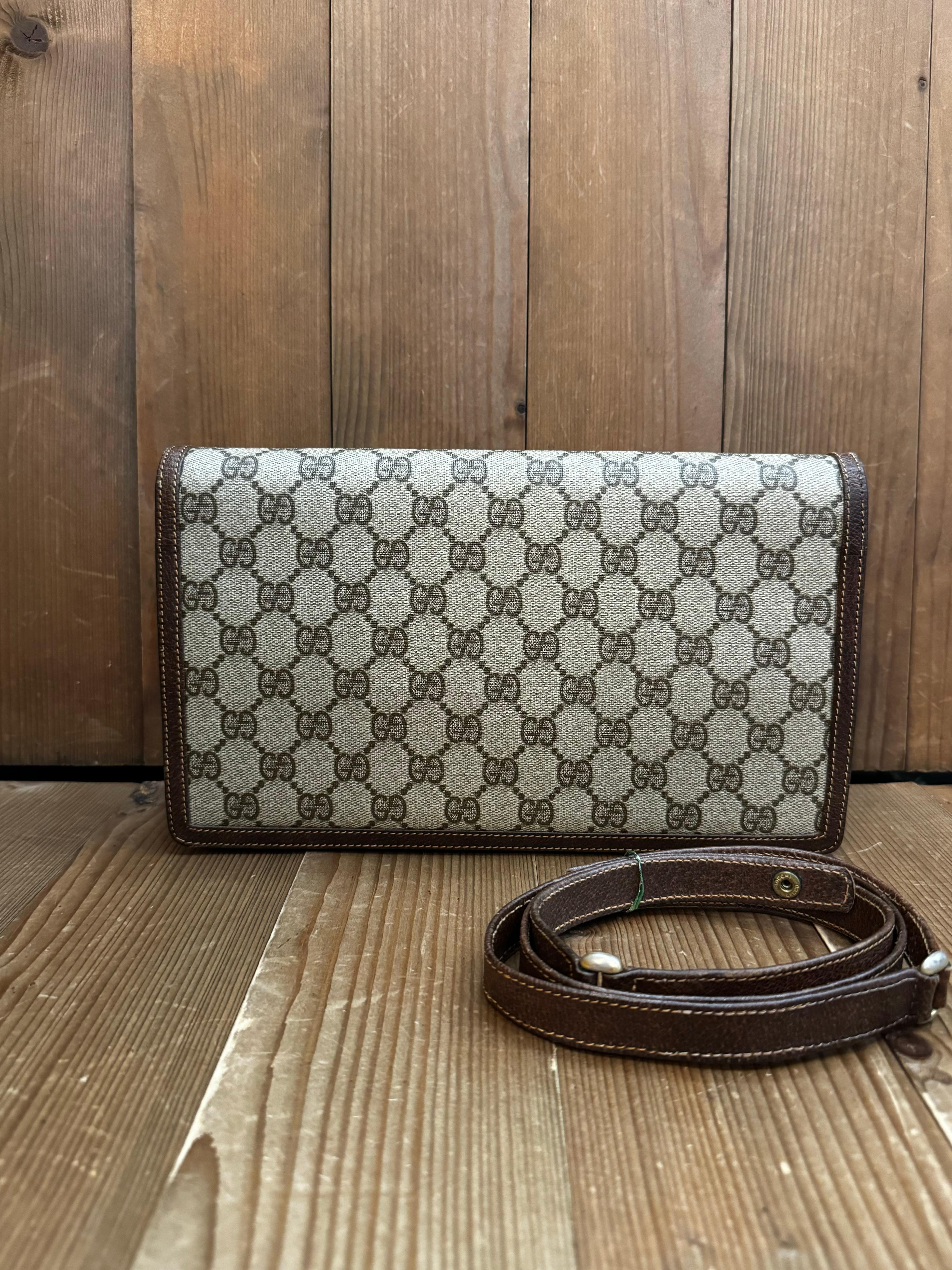 This vintage GUCCI BOUTIQUE two-way shoulder/clutch bag is crafted of GG monogram coated canvas and pigskin leather in brown featuring a gold toned horsebit detail. Front flap snap closure opens to a leather interior with a zippered pocket. This