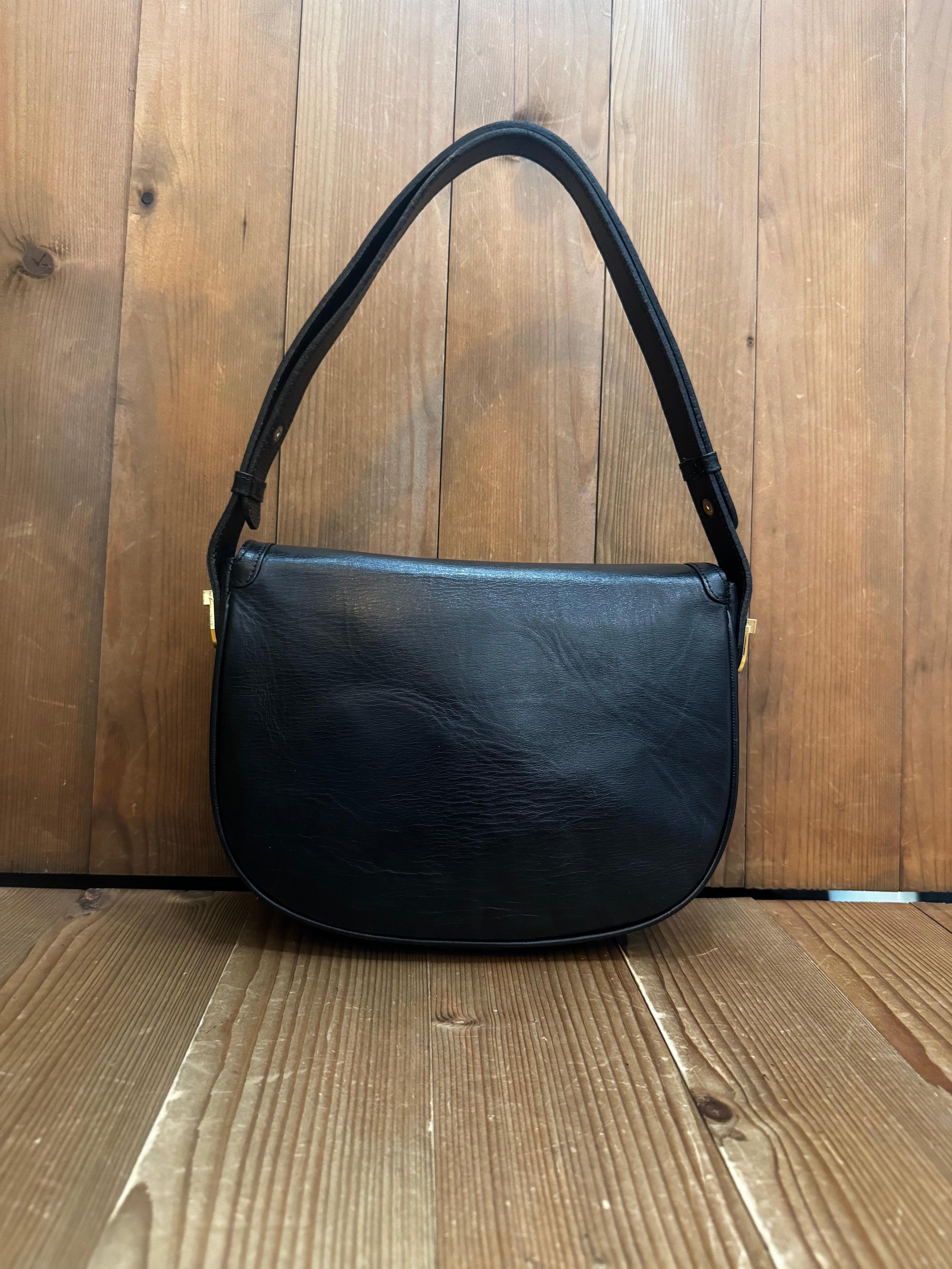 This Vintage GUCCI shoulder bag is crafted of calfskin leather in black featuring gold toned hardware. Front snap flap closure opens to a fabric interior featuring a zippered pocket and a patch pocket. Made in Italy. Measures approximately 10 x 8 x