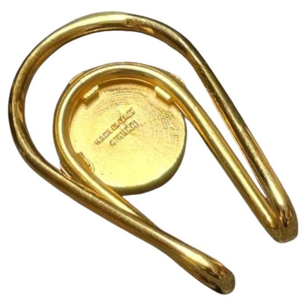 Eleganza da country club anni '70, fermasoldi Gucci in tonalità oro, caratterizzato da un disegno di pallina da golf in rilievo al centro e presentato nella sua scatola originale Gucci verde scuro con stemma in oro, Metallo in tonalità oro con