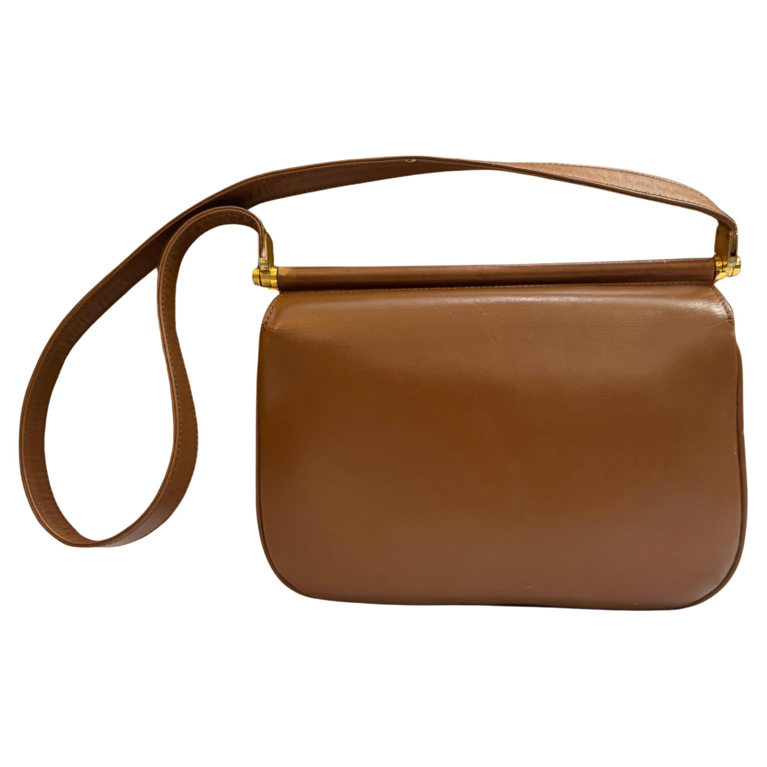 This vintage GUCCI shoulder bag is crafted of calfskin leather in brown featuring gold toned hardware. Front flap turnlock closure opens to two main compartments of black leather interior featuring a zippered pocket and a patch pocket. Made in