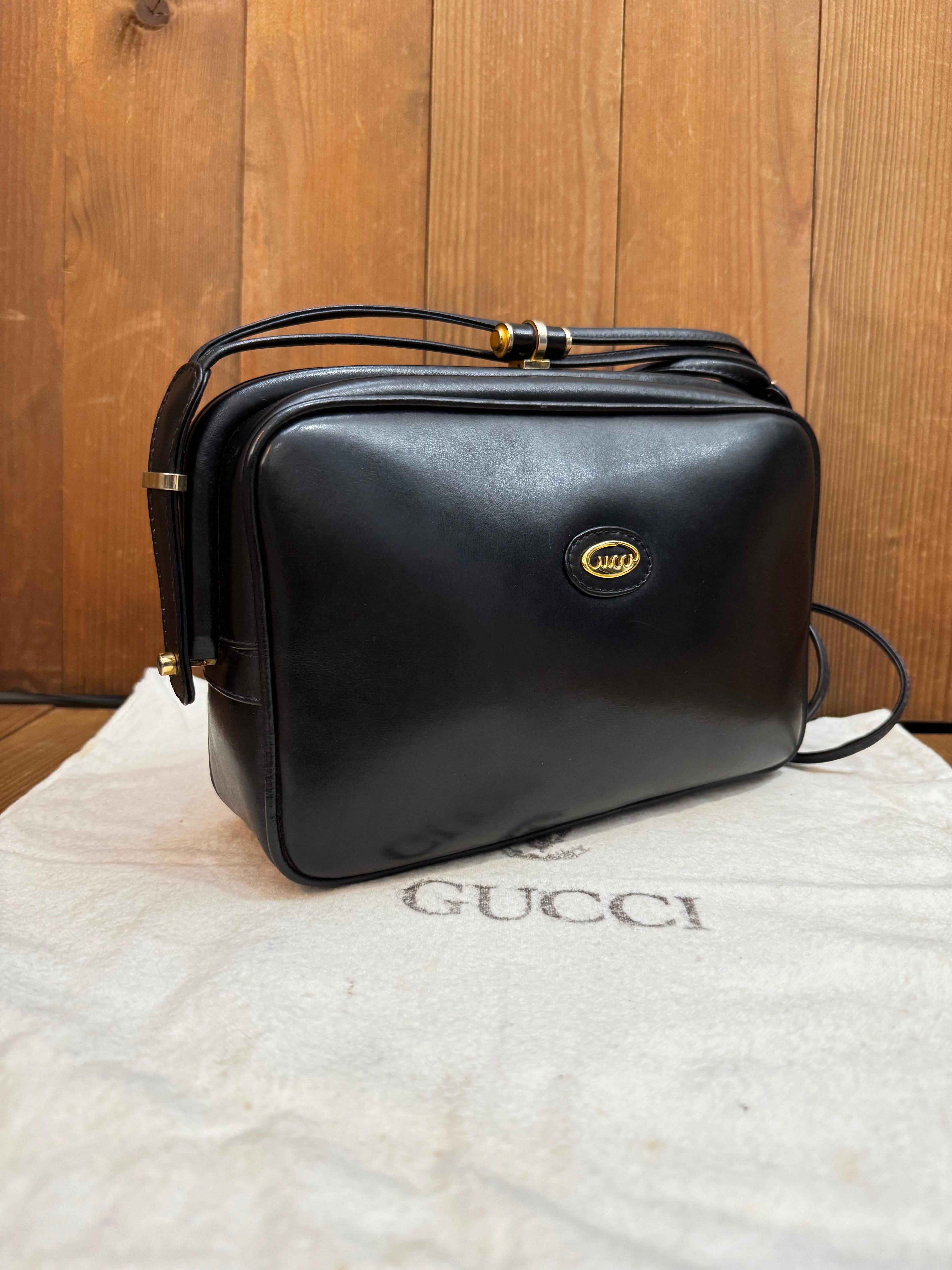 This vintage GUCCI shoulder/crossbody bag is crafted of smooth calfskin leather in black featuring gold toned hardware and a double leather strap. Top kiss-lock closure opens to a beige leather interior featuring a zippered pocket. Made in Italy.